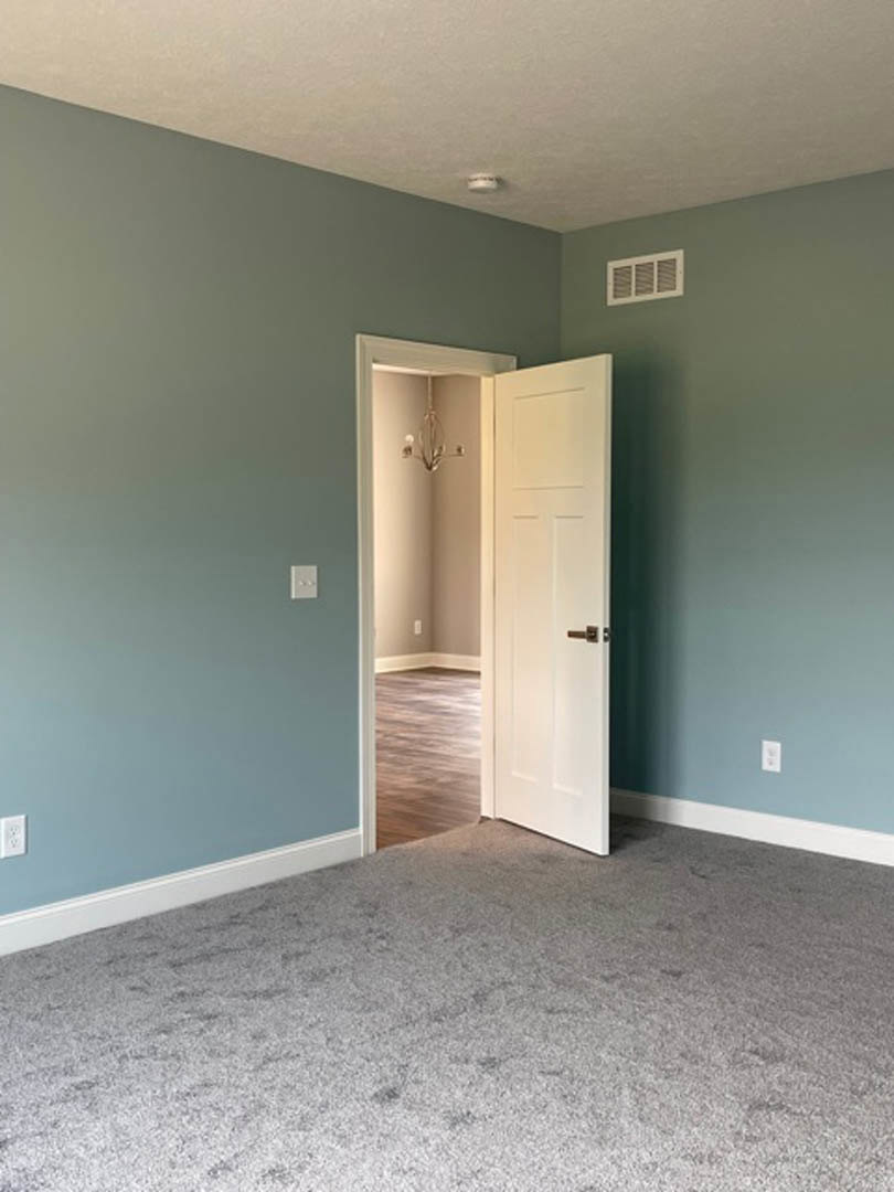 White paneled door open to a carpeted room with light-colored walls, plaster ceiling, and recessed lighting fixture