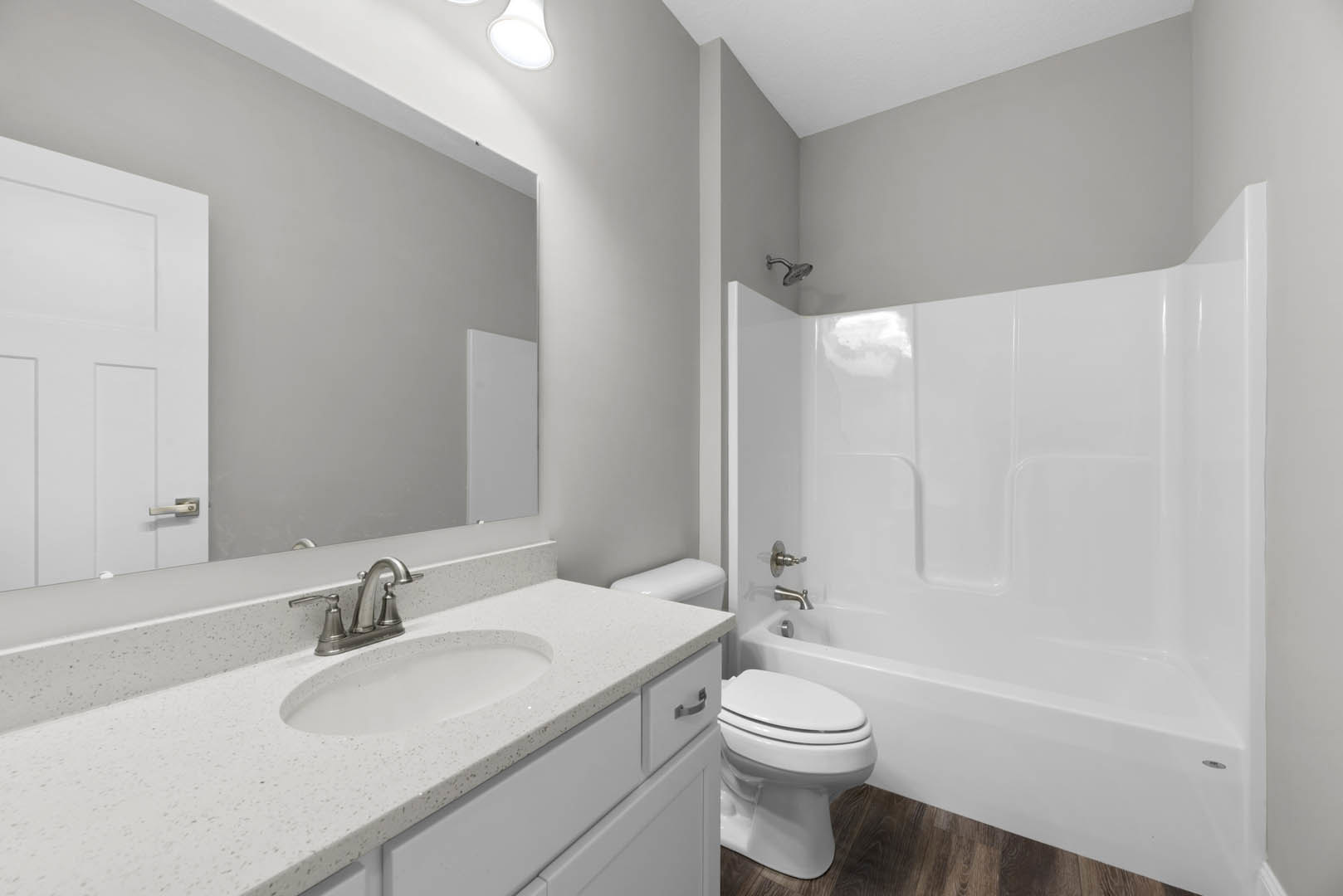 Modern bathroom featuring a white bathtub, tiled walls, single sink with chrome faucet, and a closed white toilet adjacent to a paneled door.