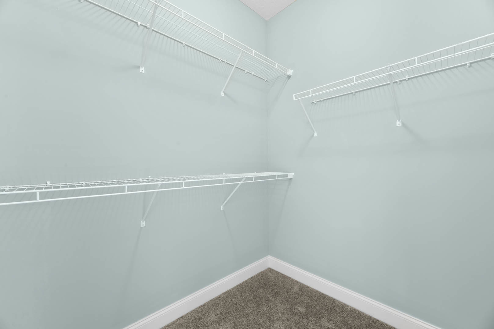 White built-in shelves against a smooth white wall, tile flooring, and plaster ceiling in a modern bathroom interior.