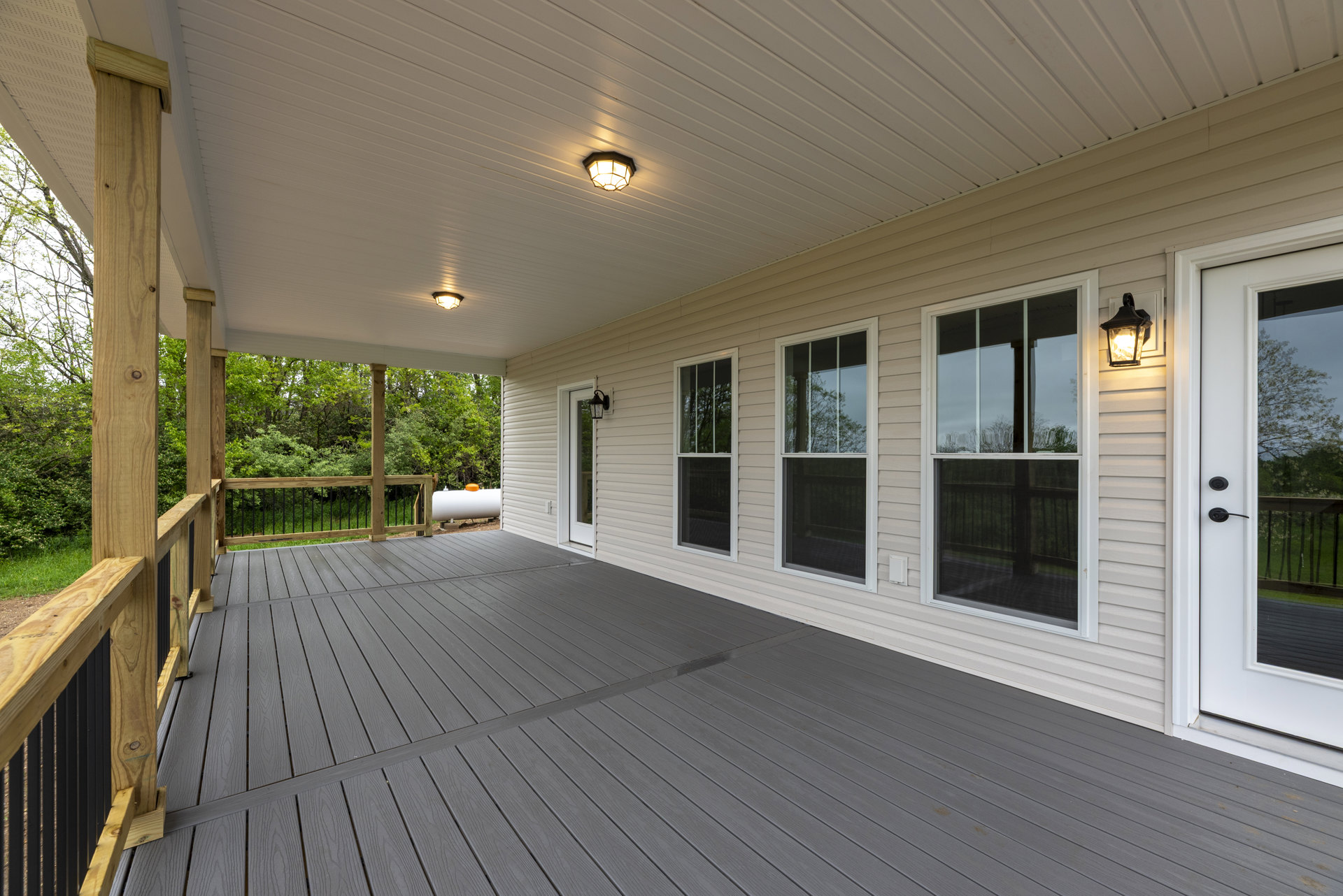 Spacious deck with wood flooring, white wall, large windows, glass door, and ceiling-mounted light fixtures