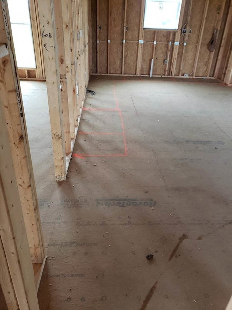 Vaulted ceiling with exposed wood beams, large window framed by wooden trim, light hardwood flooring