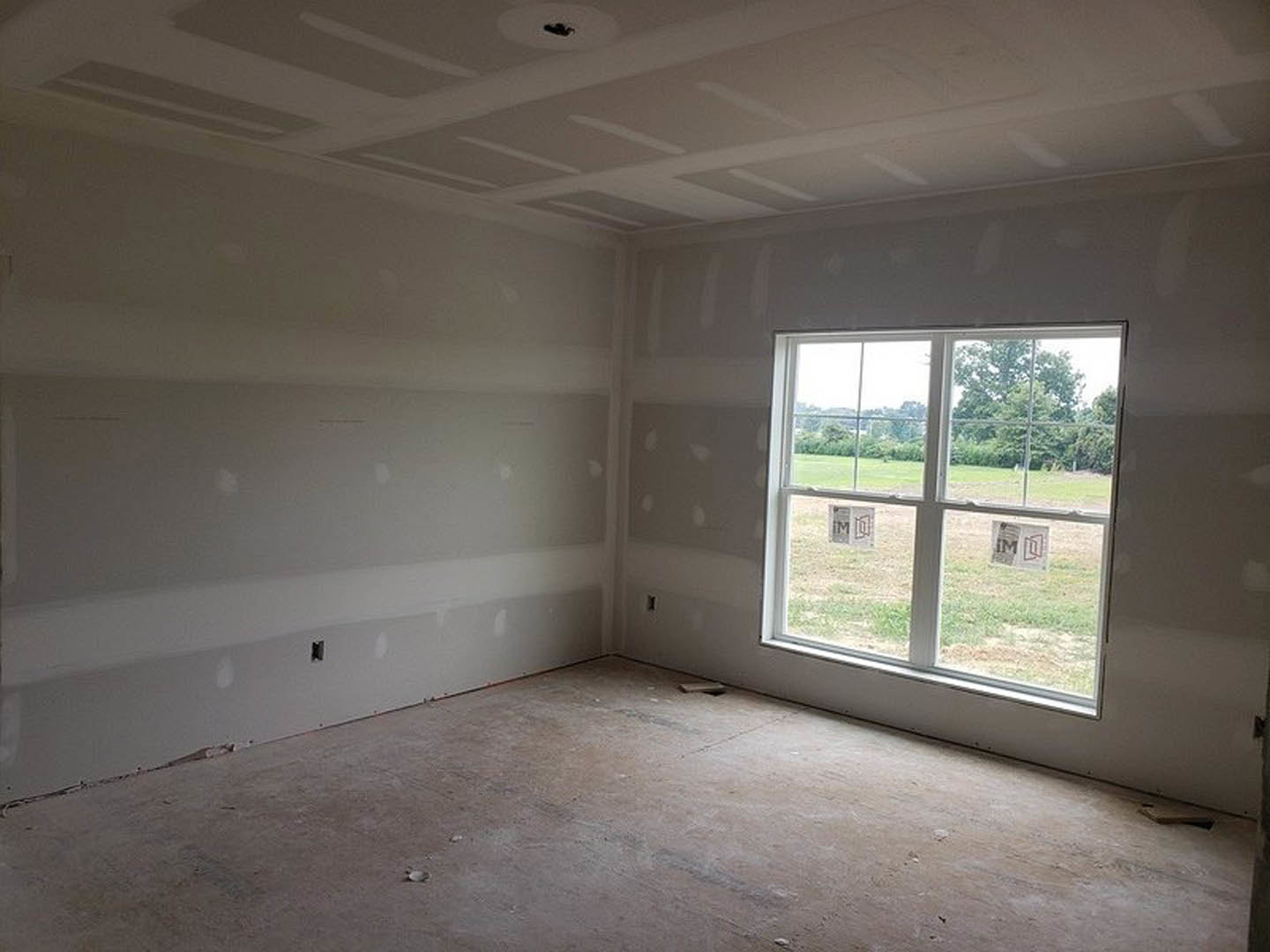 Modern room featuring two large windows, smooth plaster walls, exposed concrete floor, recessed ceiling light, and a decorative bird silhouette logo on the glass.