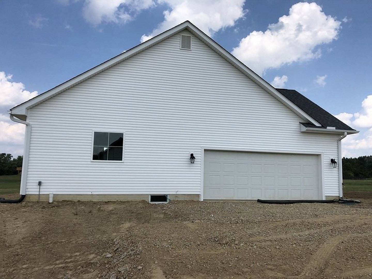 White clapboard house with attached garage, white garage door, gable roof, and Rockingham Meeting House visible in the background under a cloudy sky.