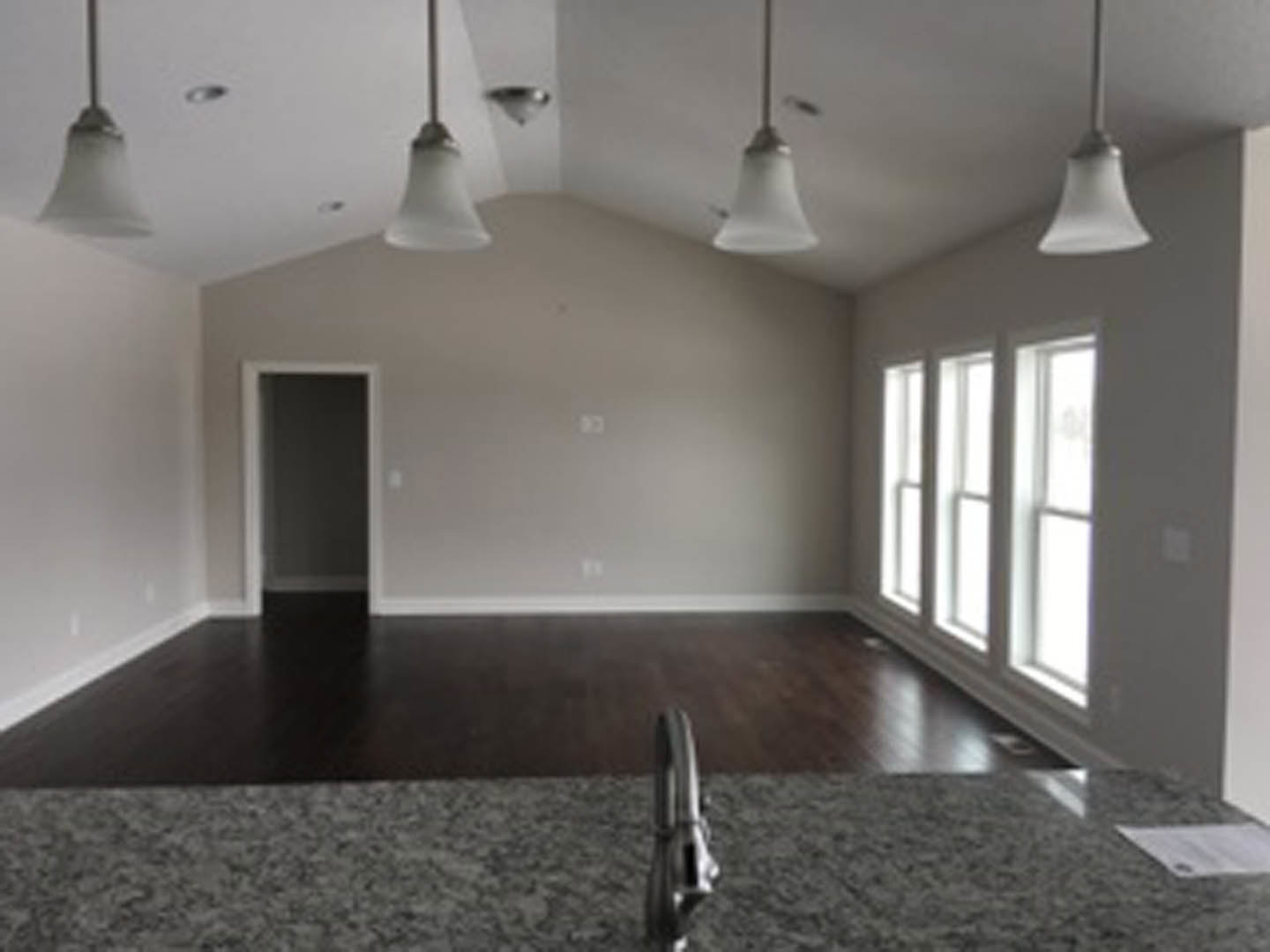 Marble countertop with stainless steel faucet, wood flooring, plaster walls, window, and ceiling fixture in a custom kitchen