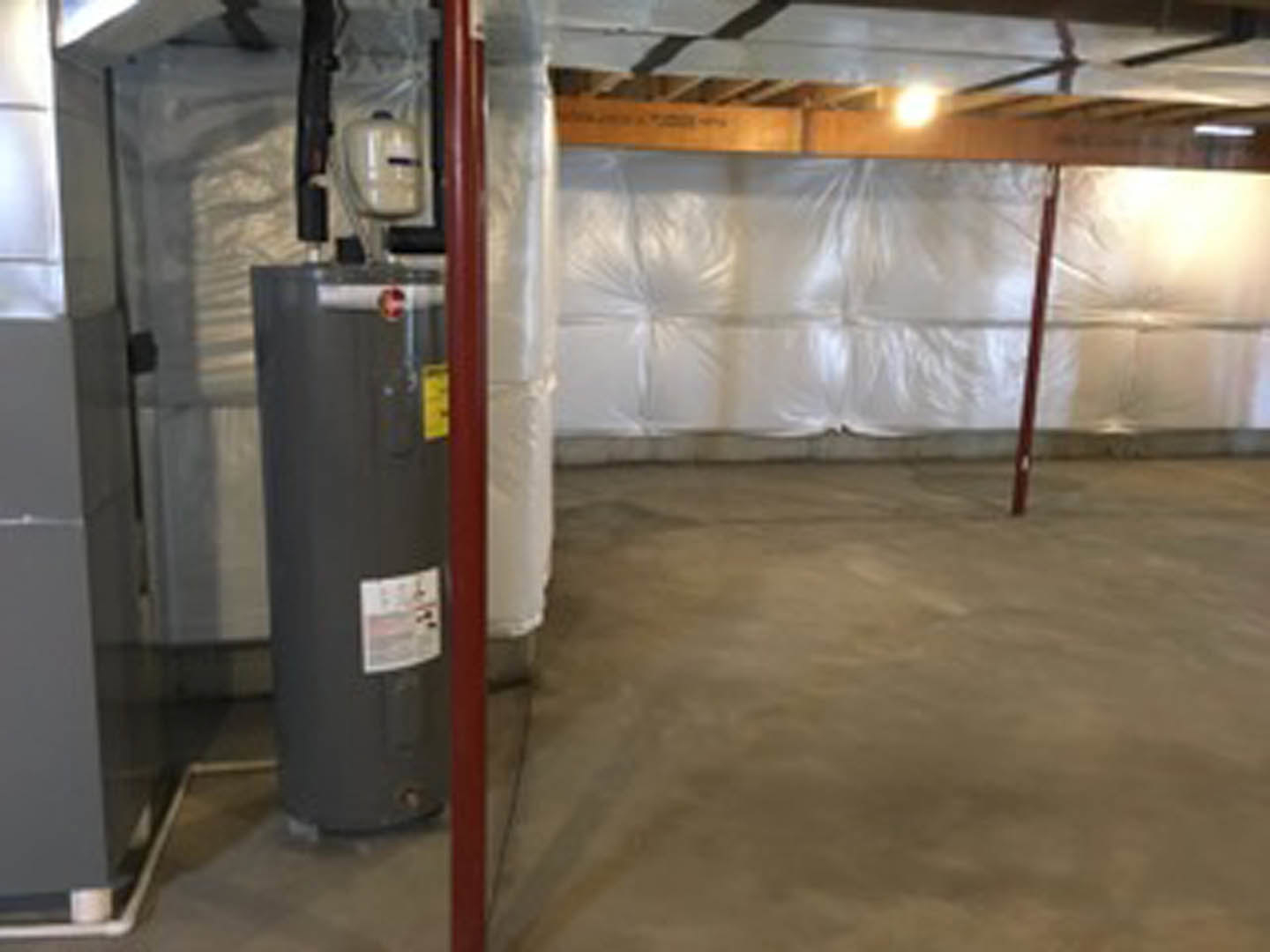 Large grey steel cylinder with yellow label positioned on concrete basement floor, surrounded by grey walls and exposed ceiling.
