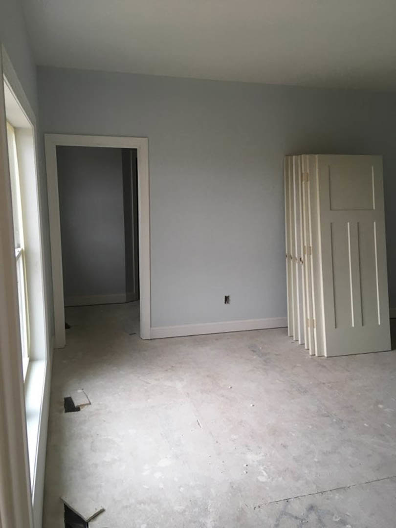 White walls, white square-panel door, white floor, plaster finishes, minimal interior detailing