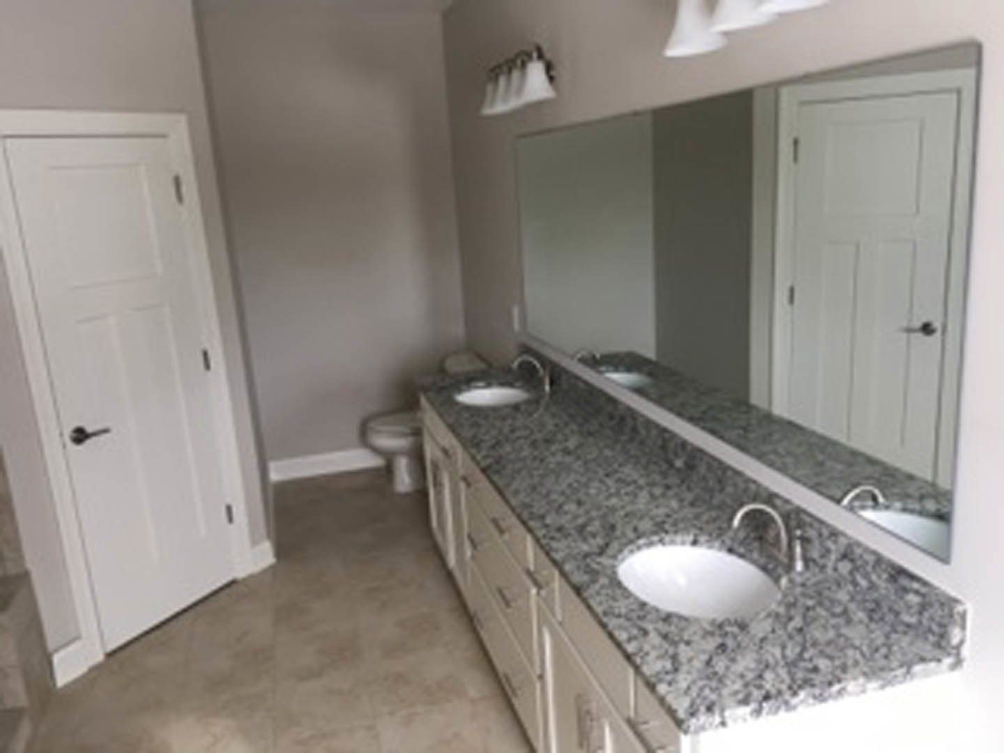 Marble bathroom countertop with undermount sink, chrome faucet, white cabinetry, and tiled backsplash