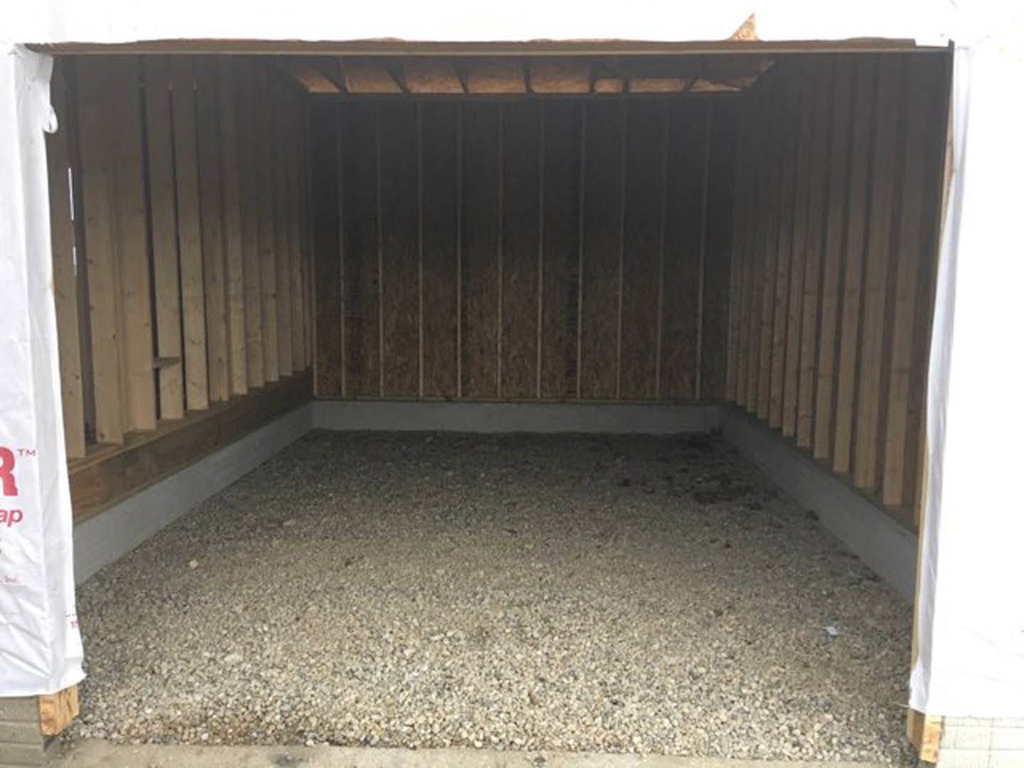 Gravel floor in a modern room with concrete walls, metal fence with wooden frame, and large window.