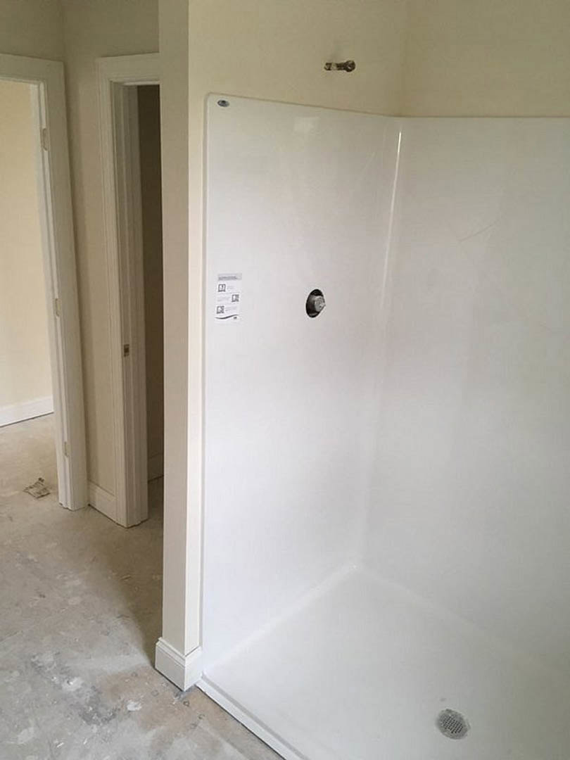 White tile shower stall with built-in niche, chrome drain, and smooth plaster walls.