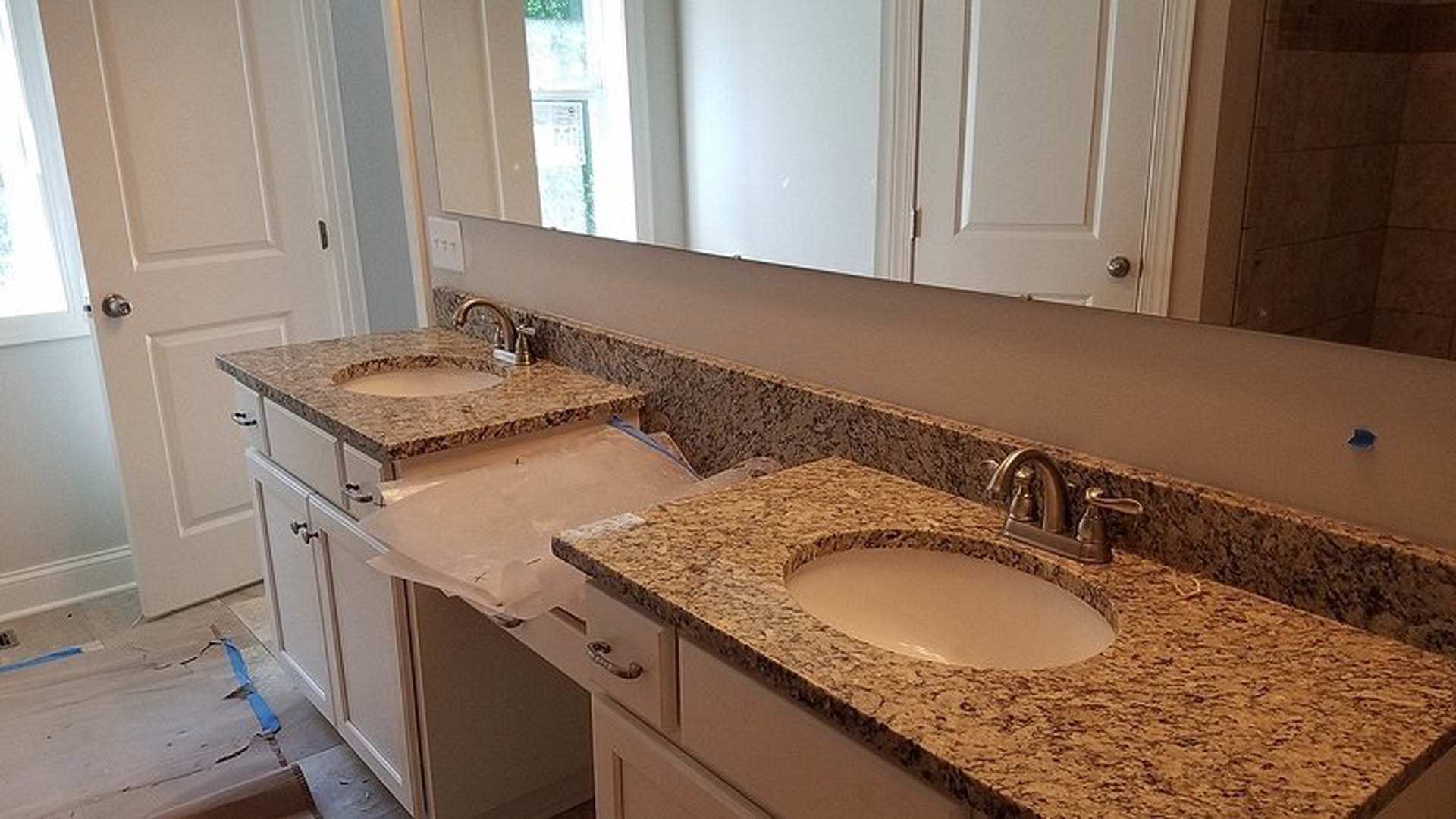 Bathroom with marble countertops, white vessel sink, chrome faucet, tile backsplash, wood cabinetry, and wall-mounted mirror