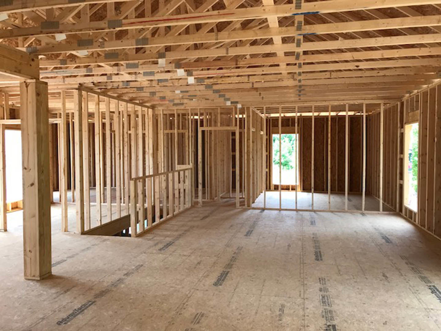 Living room with exposed wood ceiling beams, large window overlooking green trees, hardwood flooring, and neutral walls