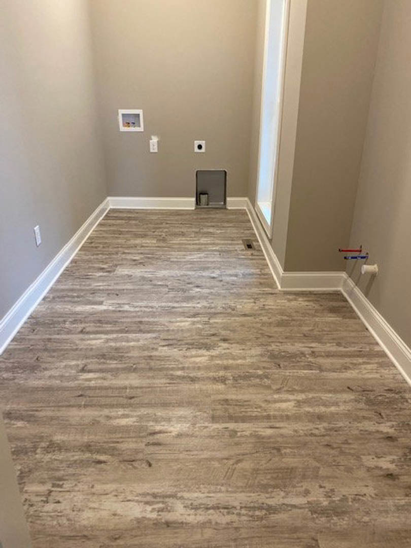 Hallway with light wood flooring, white walls, and a white framed object mounted on the wall