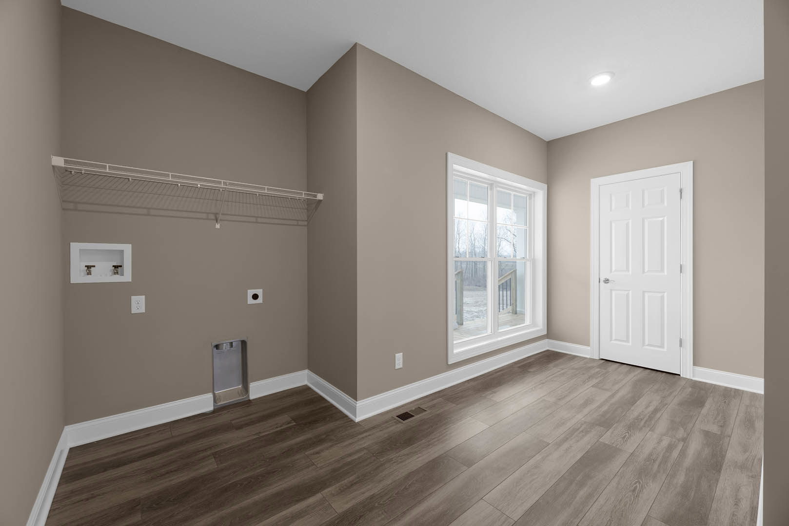 White paneled door with silver handle, wood flooring with floor vent, white shelf with two knobs, window showing outdoor view, plaster walls