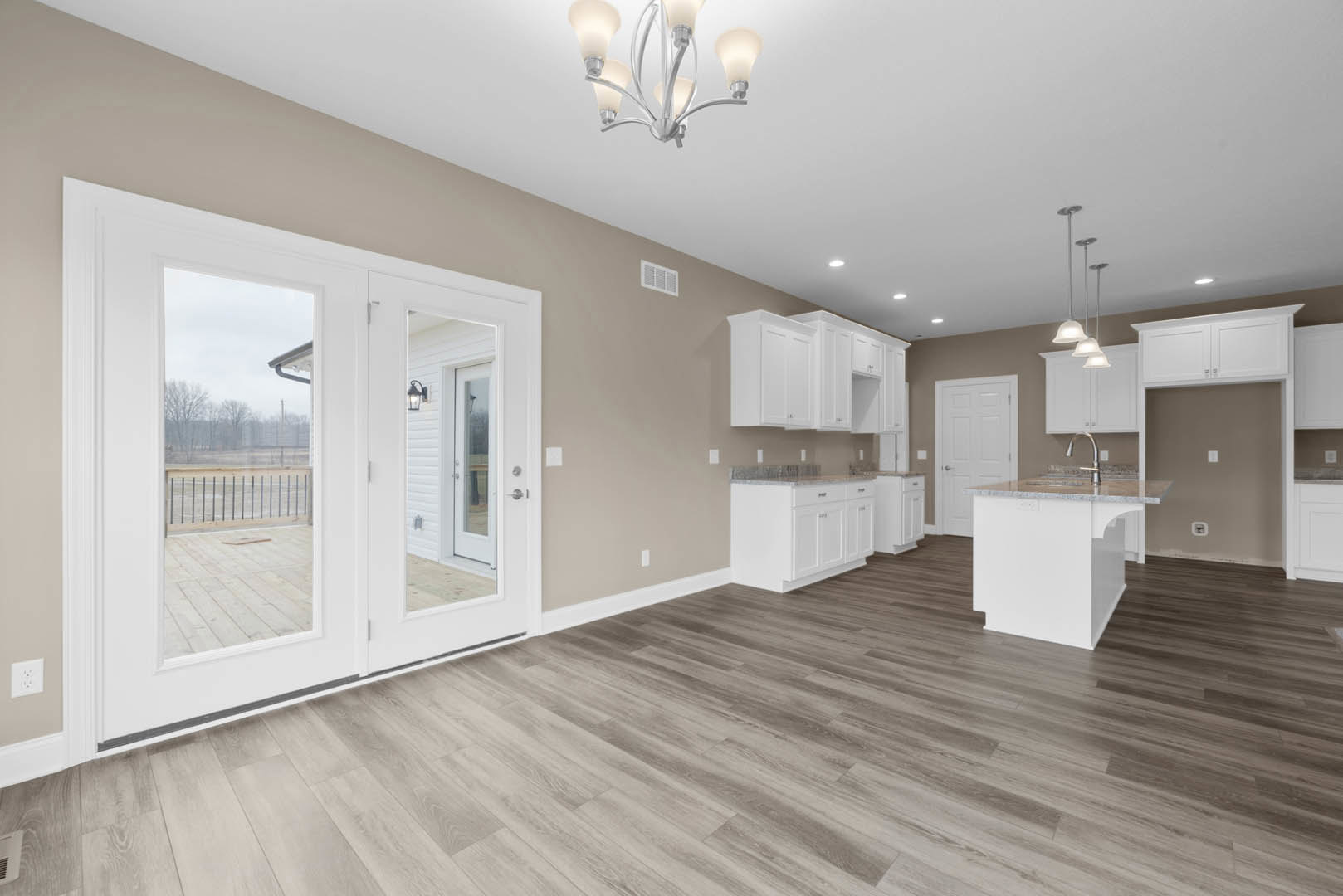 Open kitchen and dining area featuring white cabinetry, marble-topped island, hardwood floors, glass door, mirrored double doors, and a chandelier overhead.
