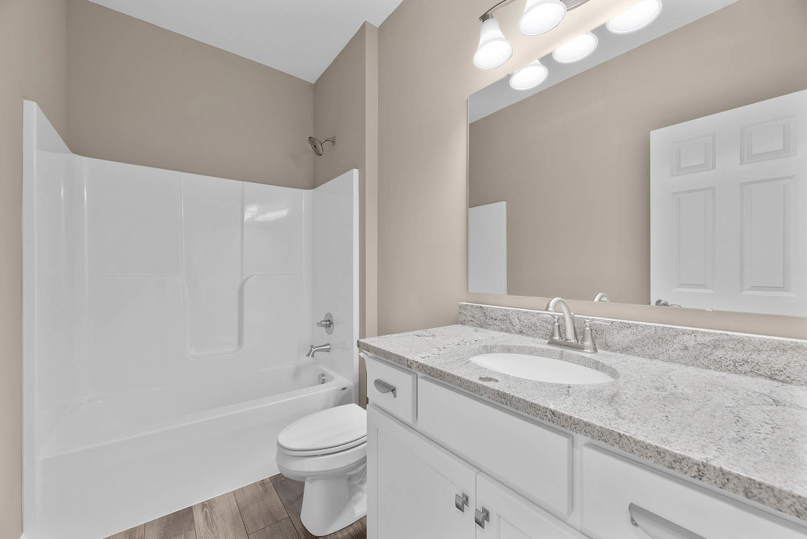 Modern bathroom with white tile walls, built-in shower with round showerhead, white porcelain sink and toilet, and a white bathtub adjacent to a paneled door.