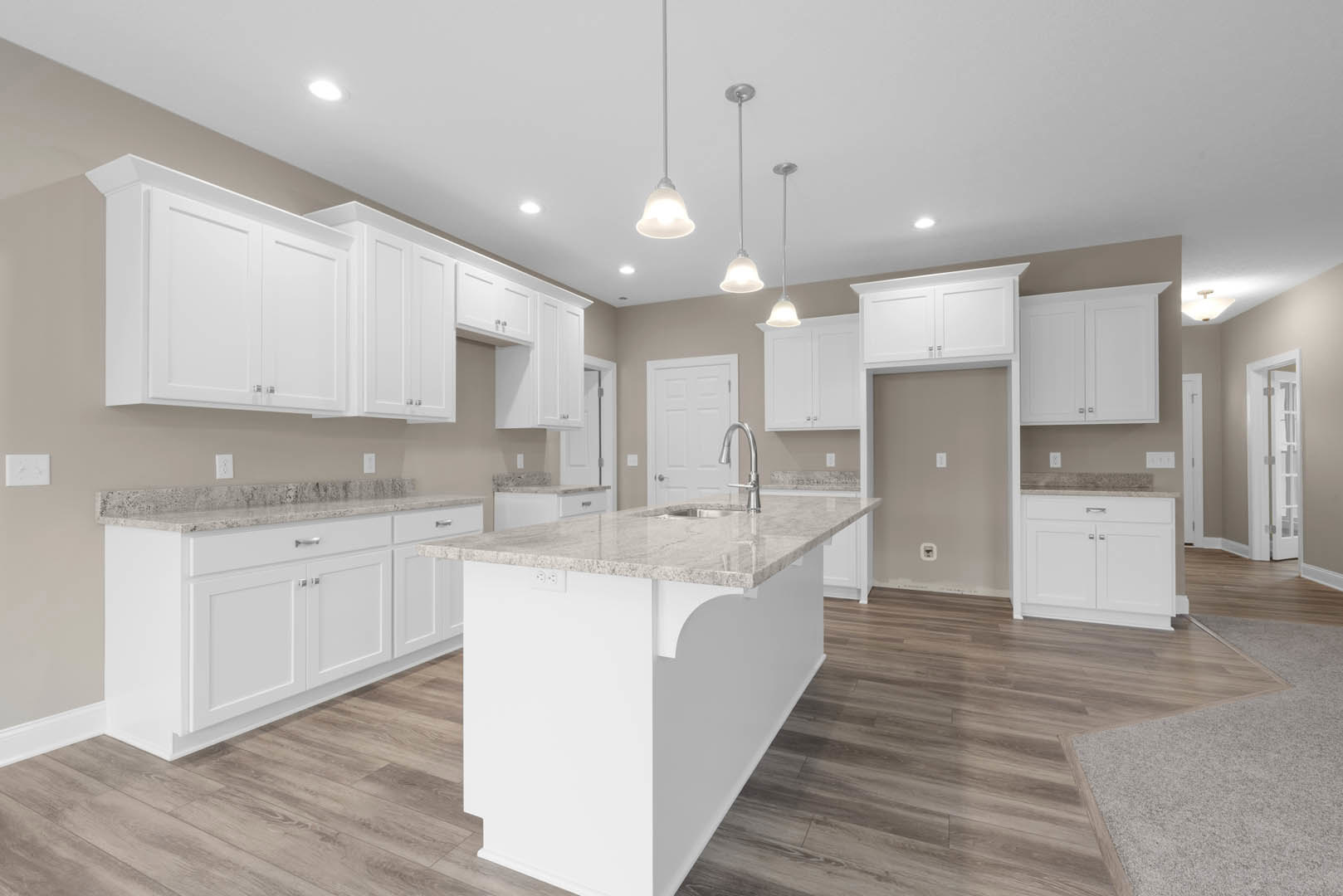 White kitchen with shaker cabinets, marble island featuring built-in sink and black faucet, pendant light fixture overhead, hardwood flooring, stainless steel appliances, and white
