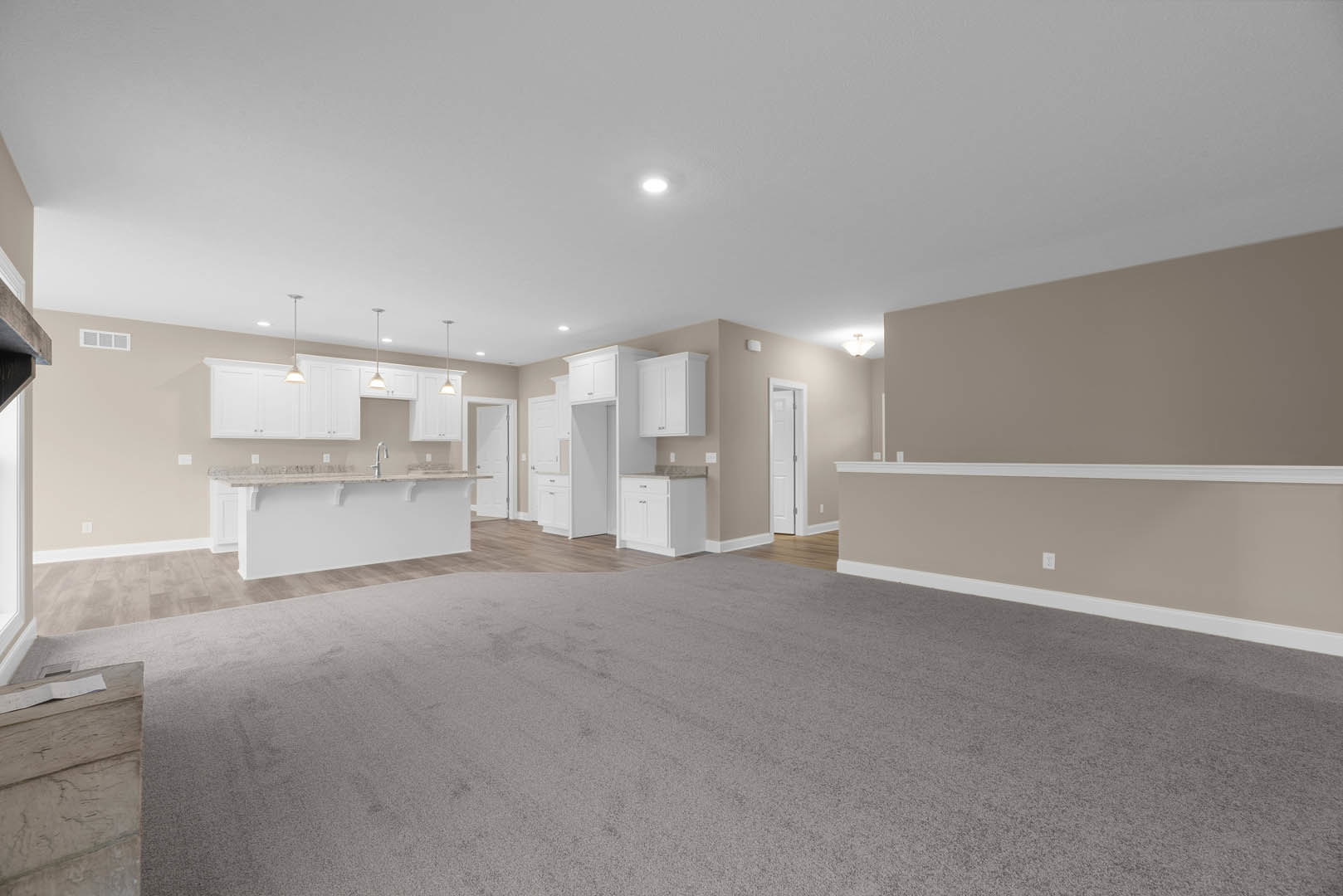 Open-concept room featuring a modern kitchen with stone backsplash, wooden flooring, white walls, and a built-in bar area.