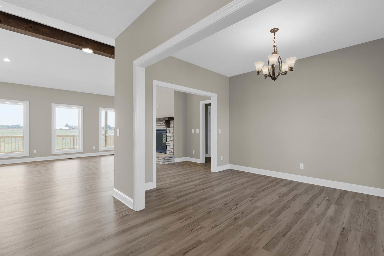 Hardwood floor room with white lamp chandelier, plaster ceiling, large window overlooking grassy field