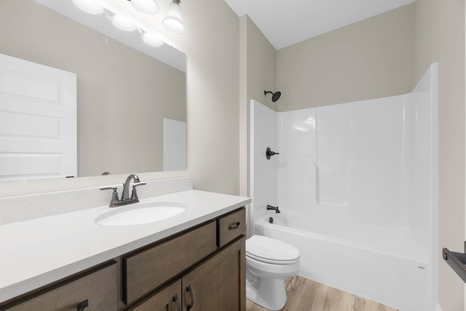 Modern bathroom featuring a white sink with drawers, black metal faucet, white toilet with closed lid, tiled walls, and a glass-enclosed shower