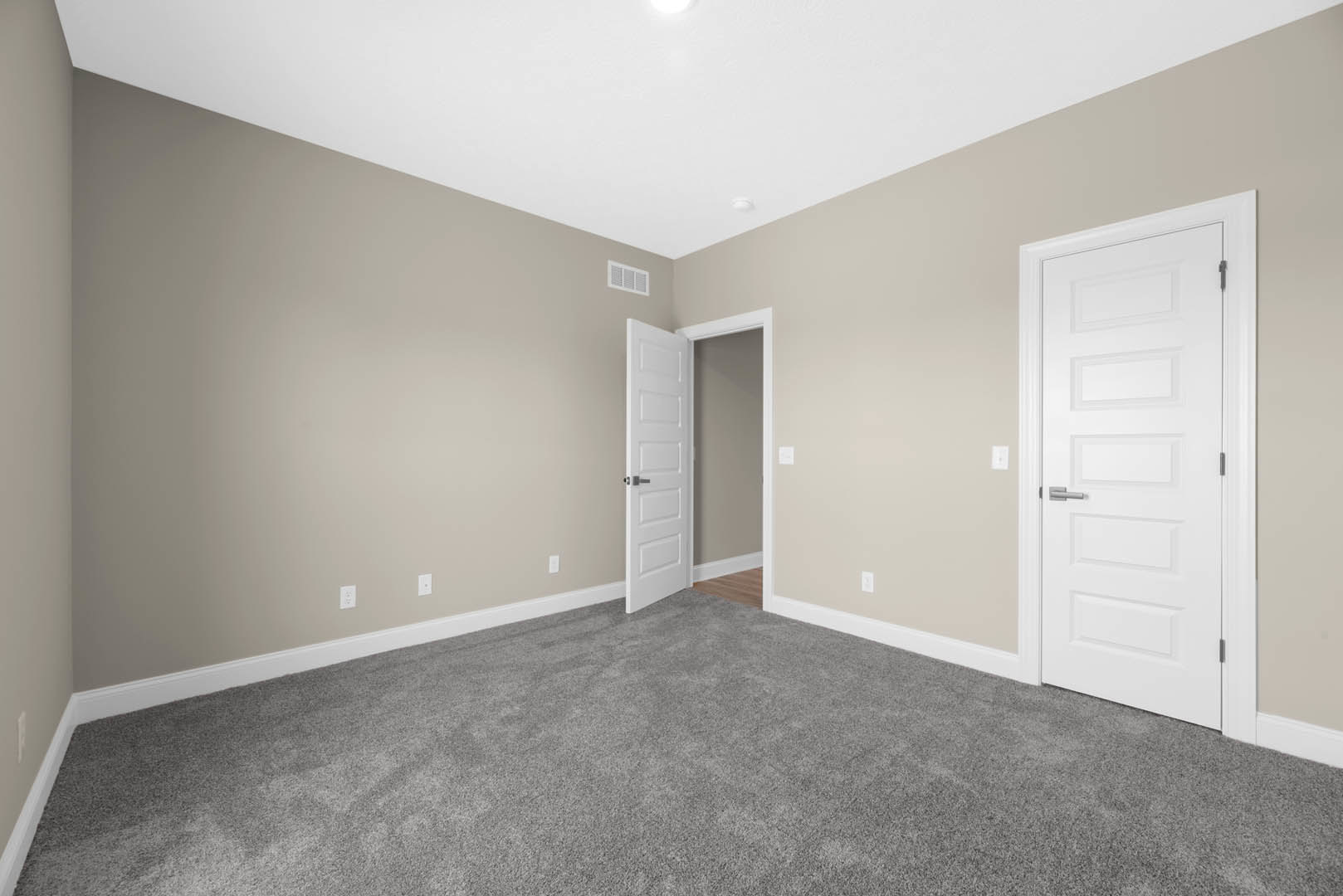 Gray carpeted room with white paneled doors, silver handles, white walls, and white ceiling