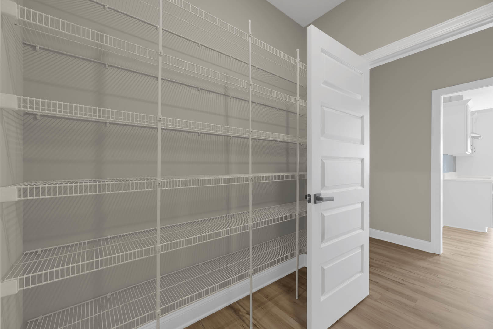 White paneled door open to a room with built-in white shelving and light-colored flooring