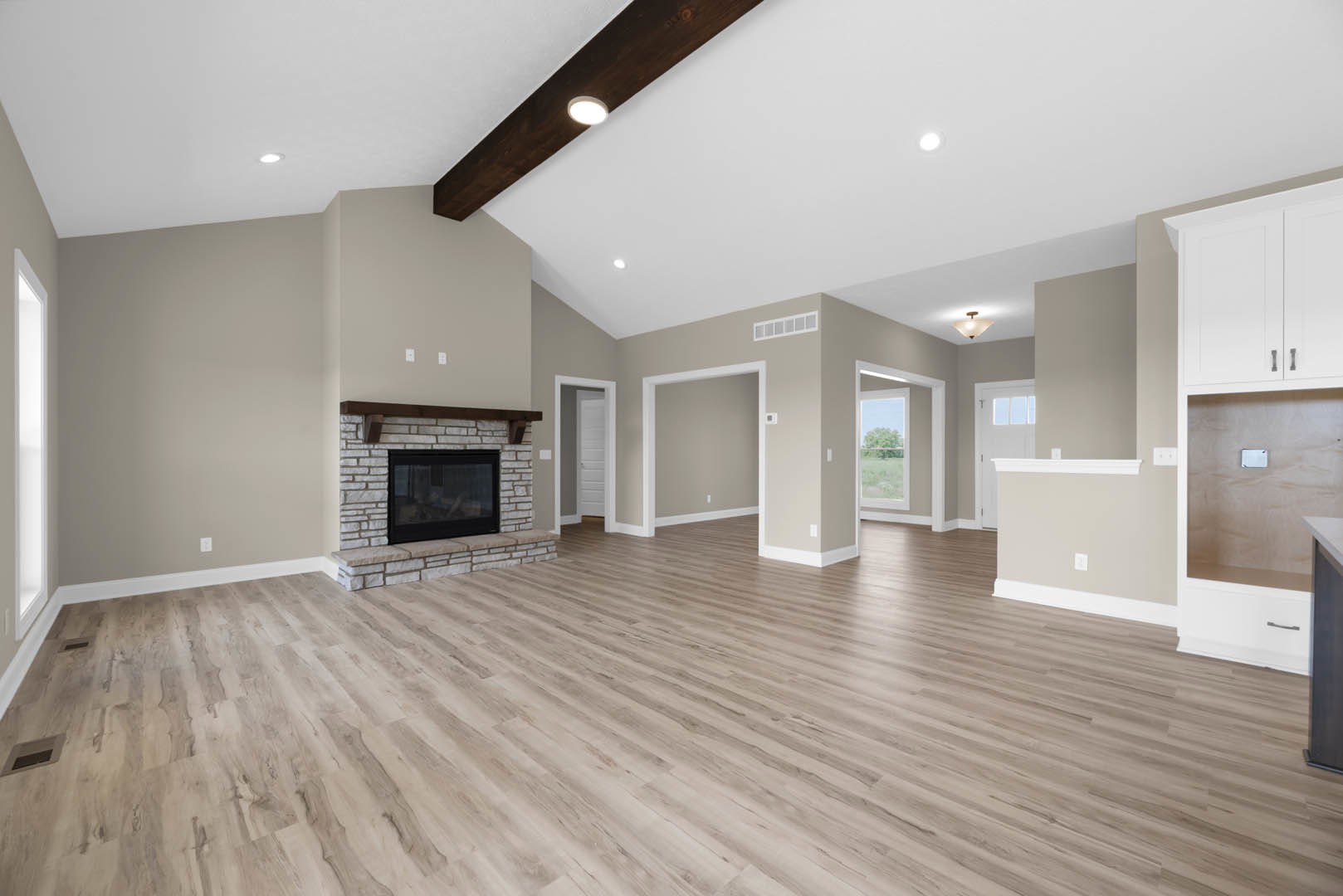 Living room with hardwood flooring, glass-front fireplace set in a white wall, sunlight streaming through window, partial view of ceiling