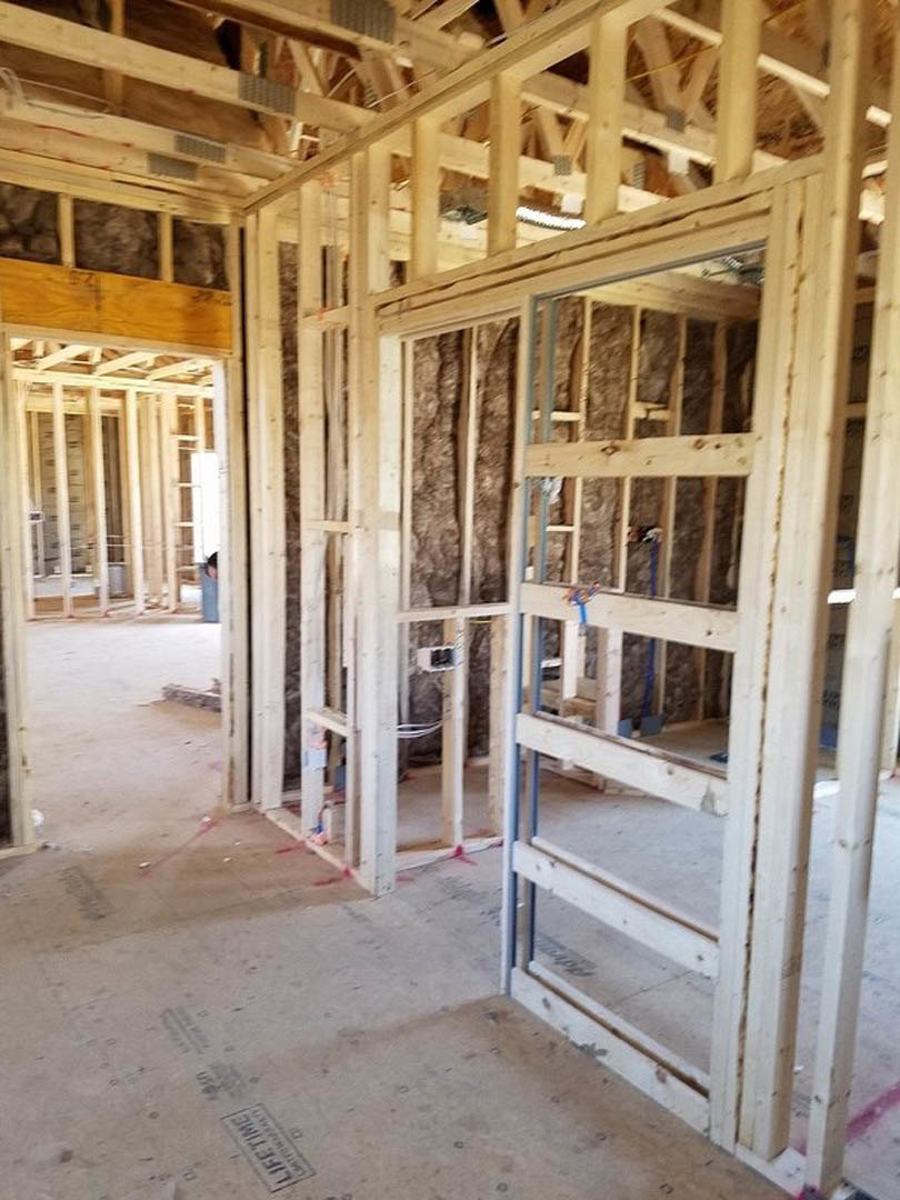 Wood-framed room under construction with exposed beams, unfinished plank flooring, and a sign placed on the ground
