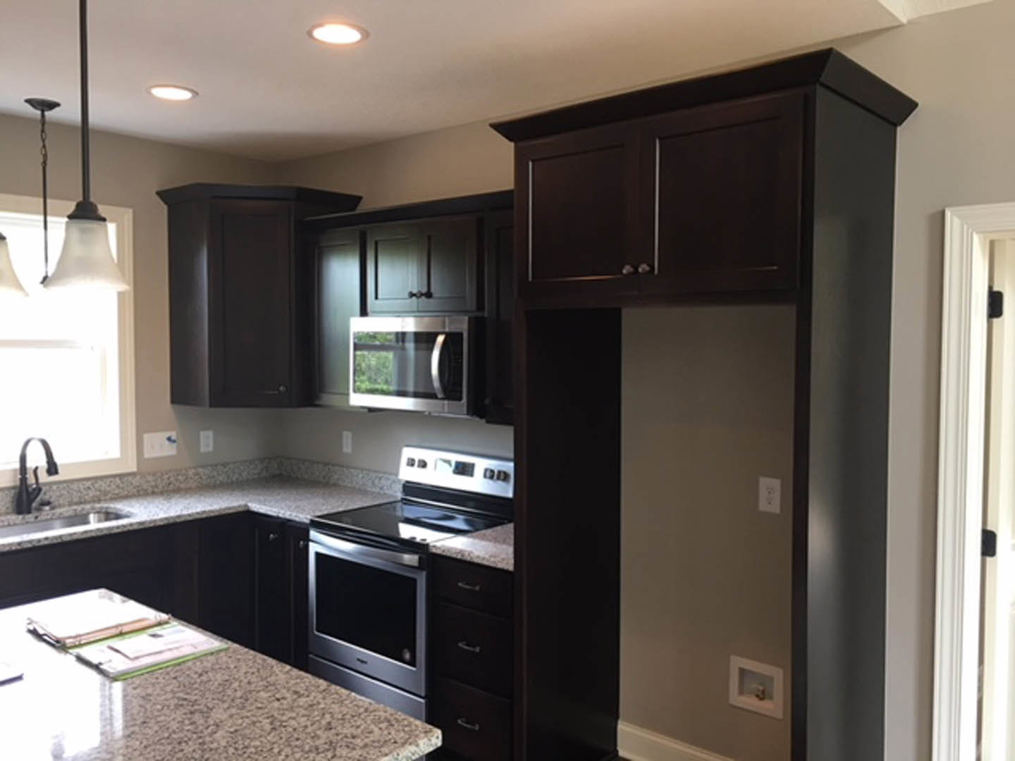 Kitchen with dark wood cabinets, light stone countertop, stainless steel appliances, and undermount sink
