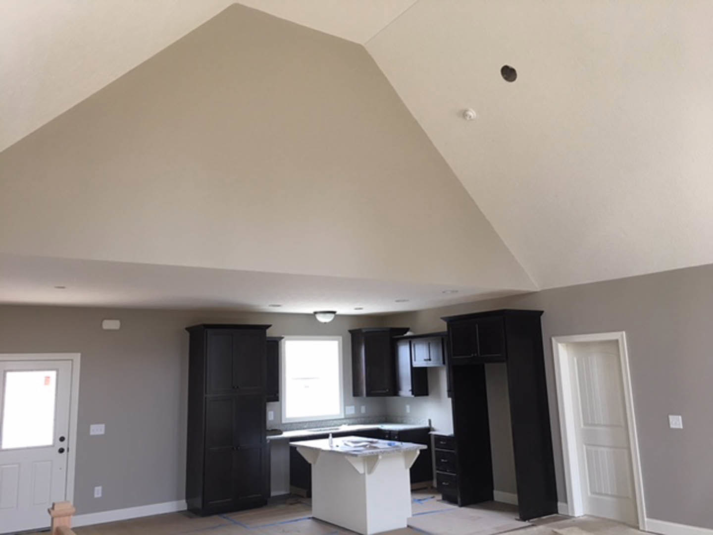 Modern kitchen with white quartz countertops, black lower cabinets, white upper cabinetry, stainless steel appliances, and a white door with glass window leading outside.