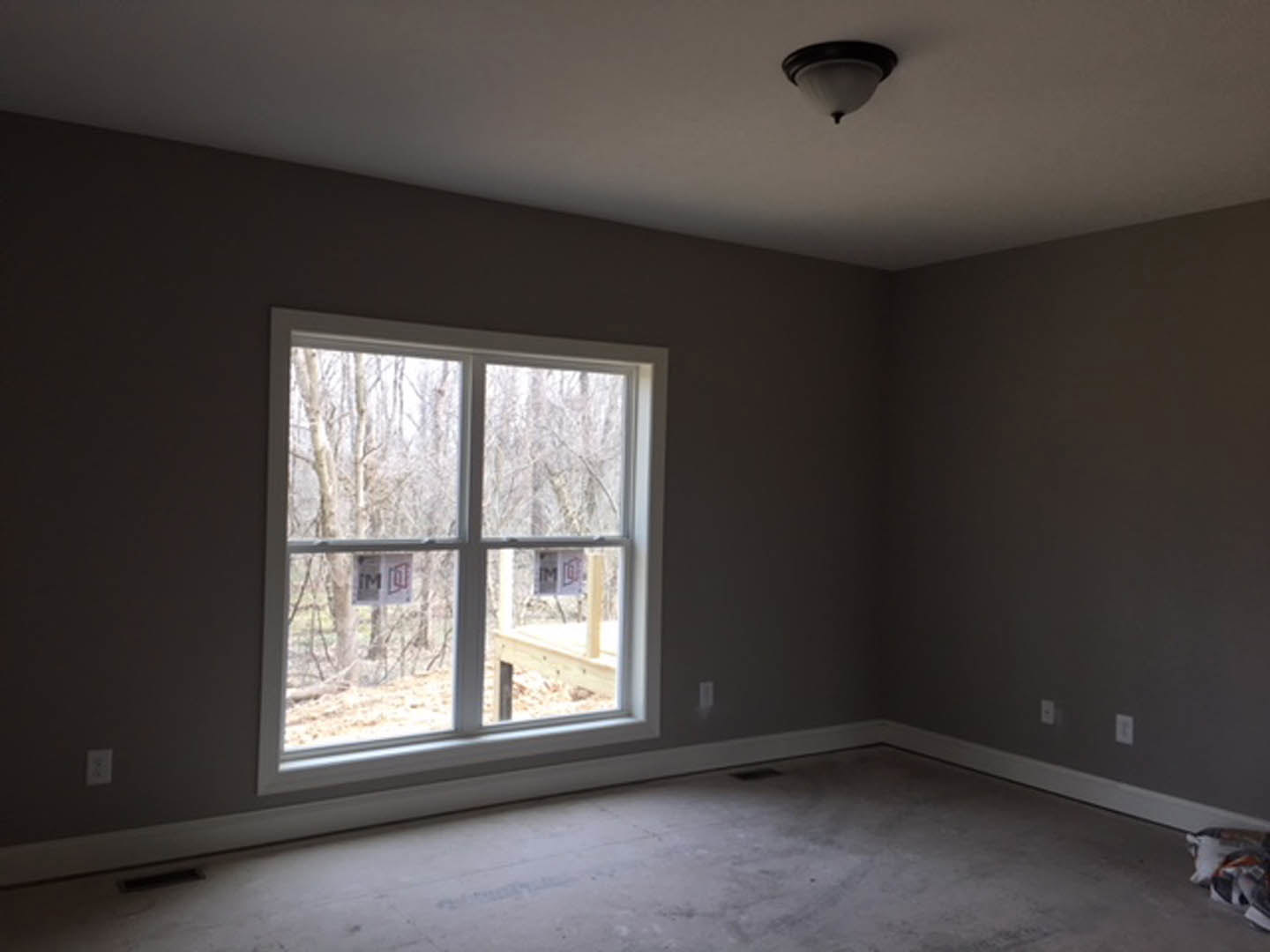 Neutral-toned room with plaster walls, large window fitted with blinds, modern ceiling light fixture, and hardwood flooring