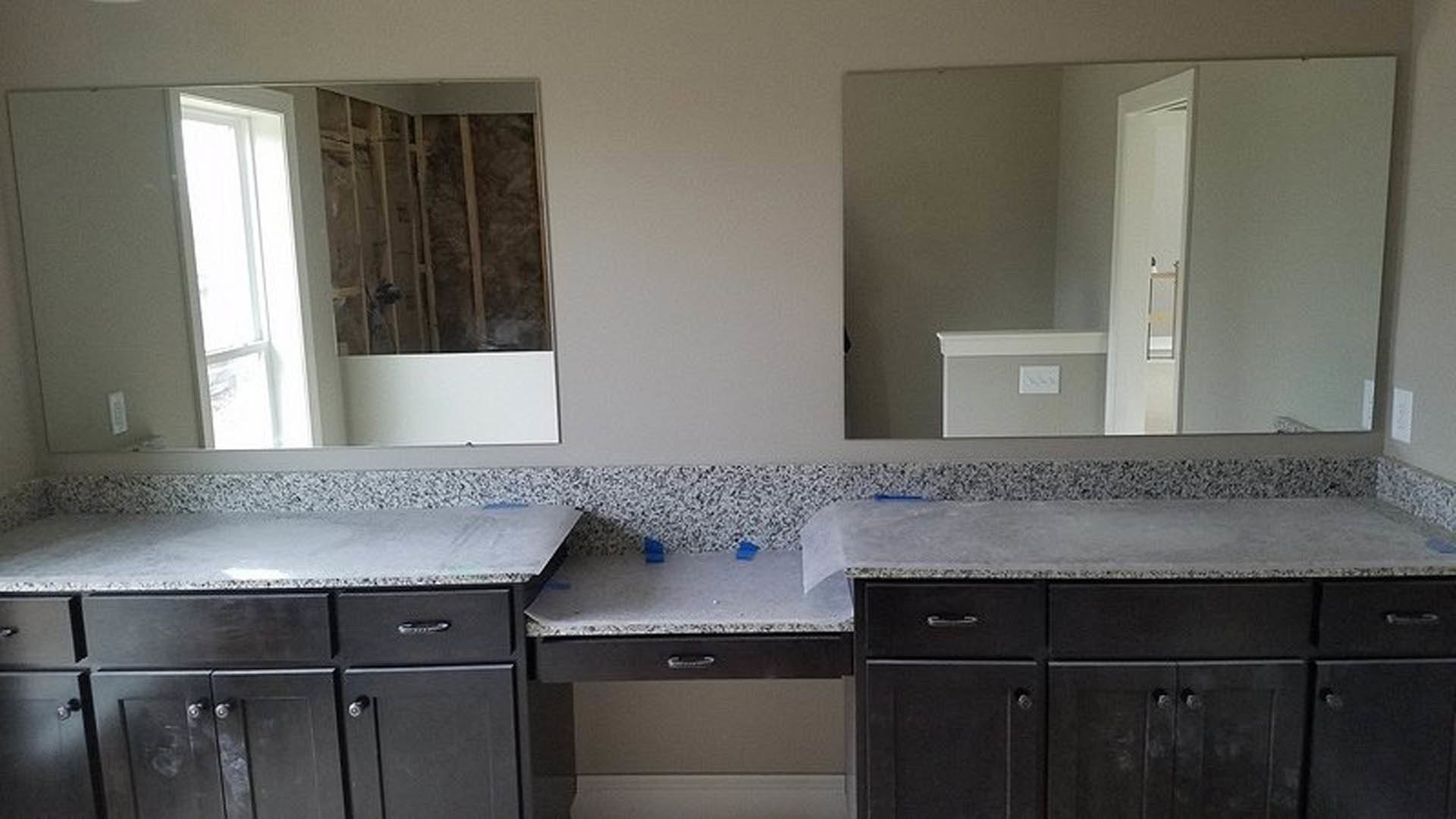 Bathroom with dual rectangular mirrors above a grey concrete countertop featuring black trim, white cabinetry, and integrated sinks.