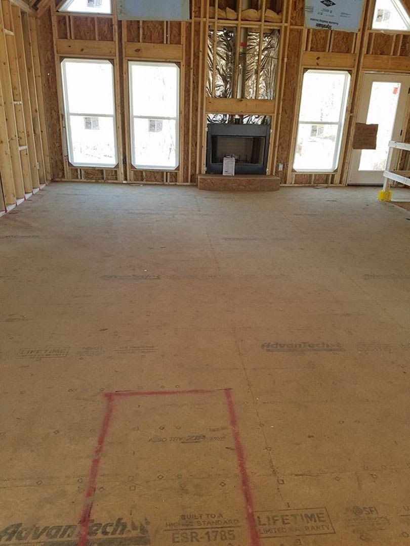 Living room with two fireplaces, concrete flooring, large window, red square accent on floor, and wall-mounted television