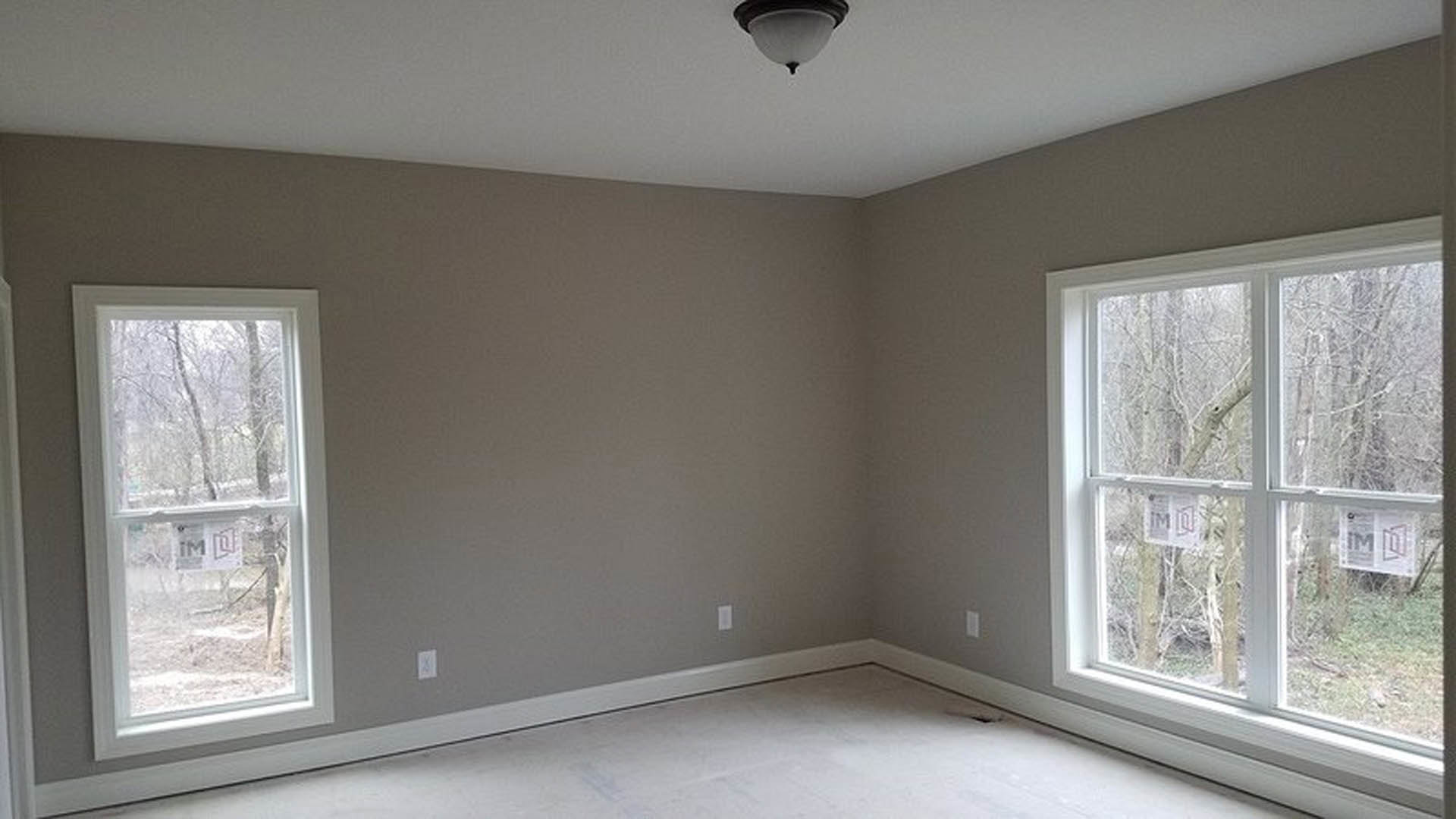 Bright room with white flooring, plaster walls, large window with blinds, and modern ceiling light fixture