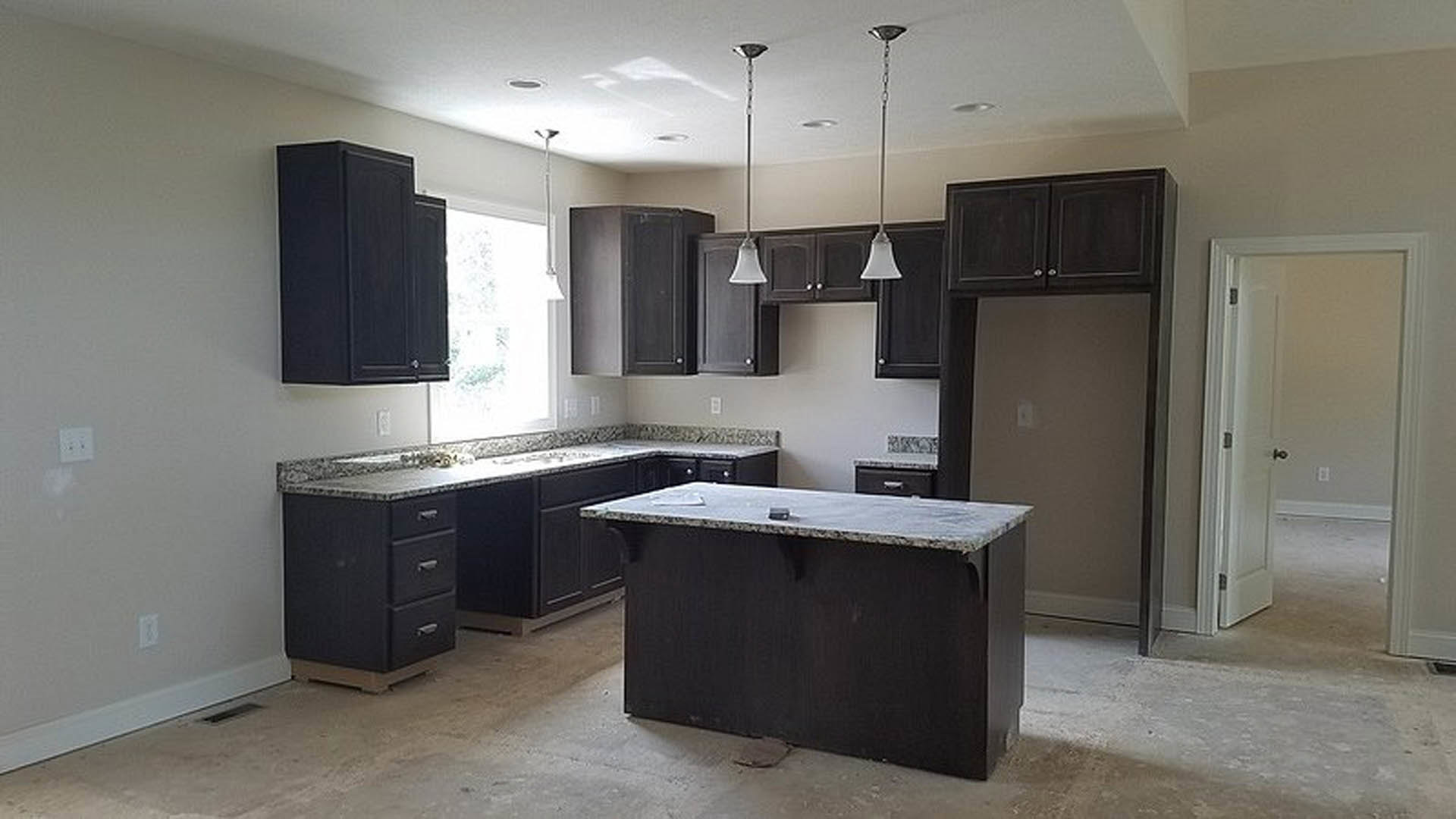 Kitchen with dark cabinetry, black and white countertops, white wall switch and electrical outlet cover, white door, tile flooring, white ceiling, built-in sink, and stainless