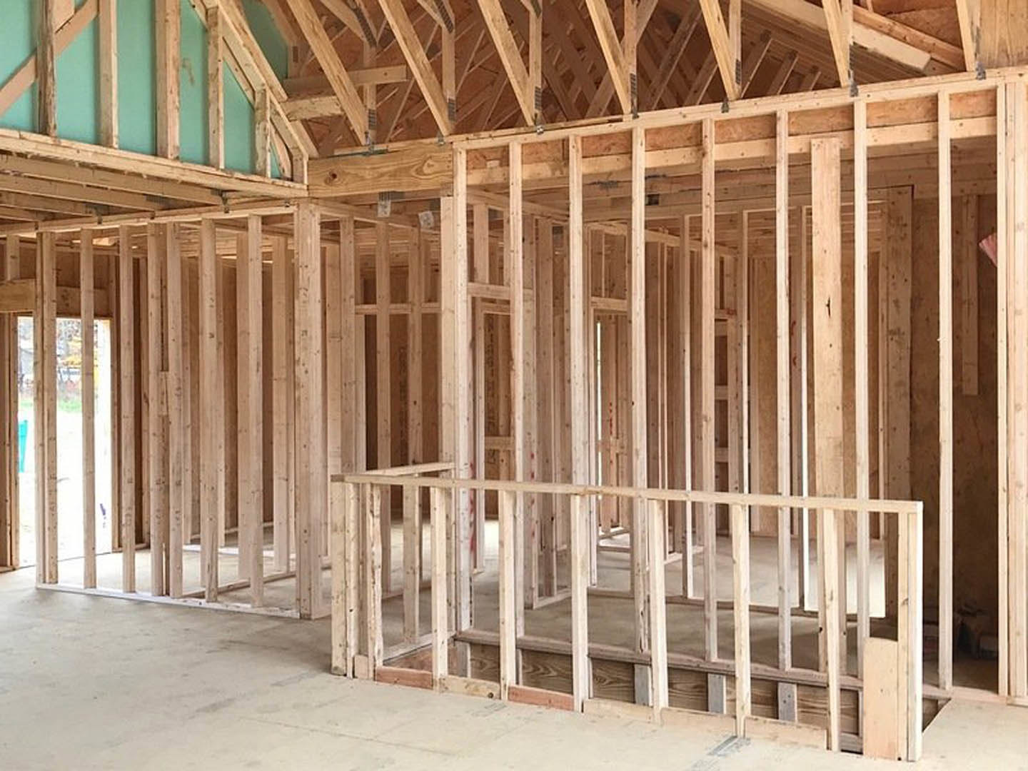 Exposed wooden framing and beams inside a partially constructed house, with unfinished walls and visible lumber