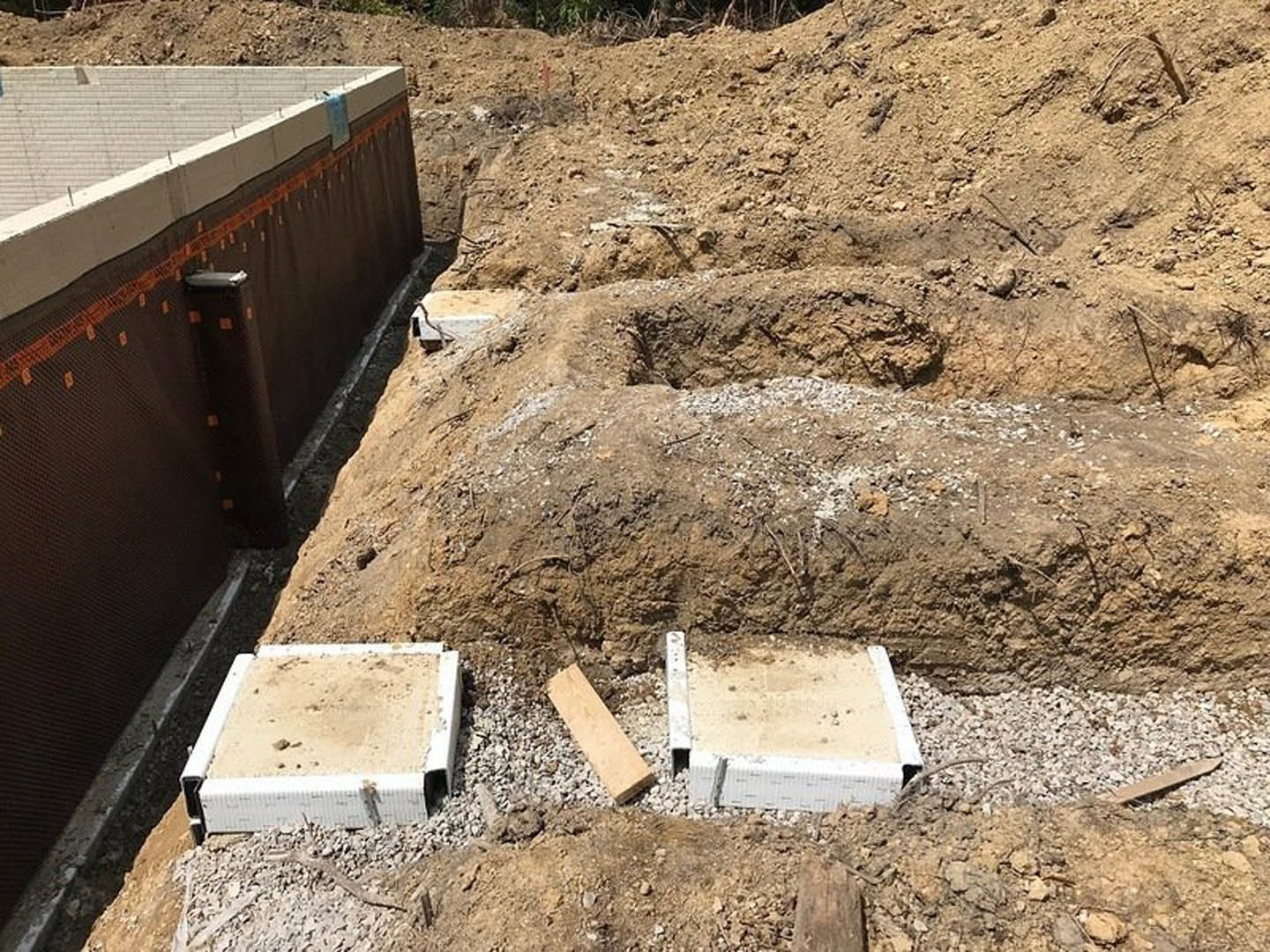 Concrete foundation slab surrounded by dirt, wood planks, and stacked concrete blocks at a residential construction site