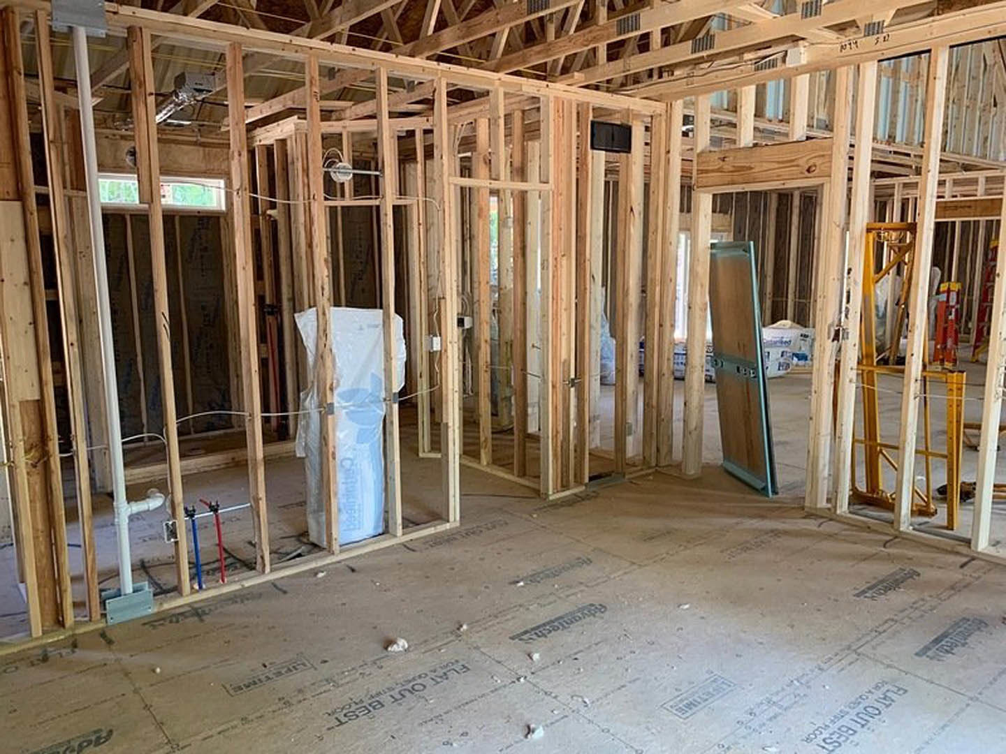 Unfinished room with exposed wood framing, large window, construction materials, and visible insulation