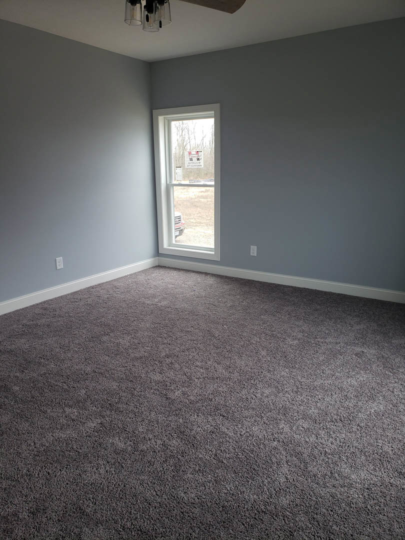 Carpeted room with white plaster walls, large window, and ceiling trim