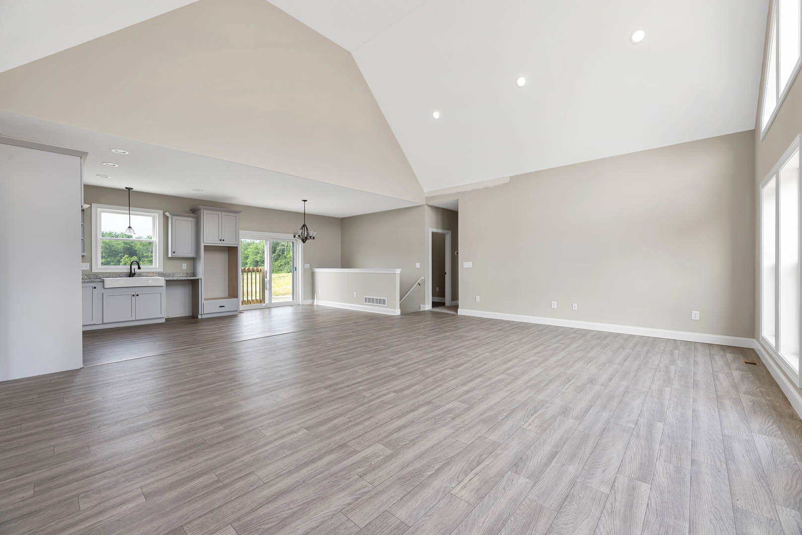 Spacious room with hardwood flooring, white plaster walls, metal bars on a door, ceiling vent, recessed ceiling light, and window letting in natural light