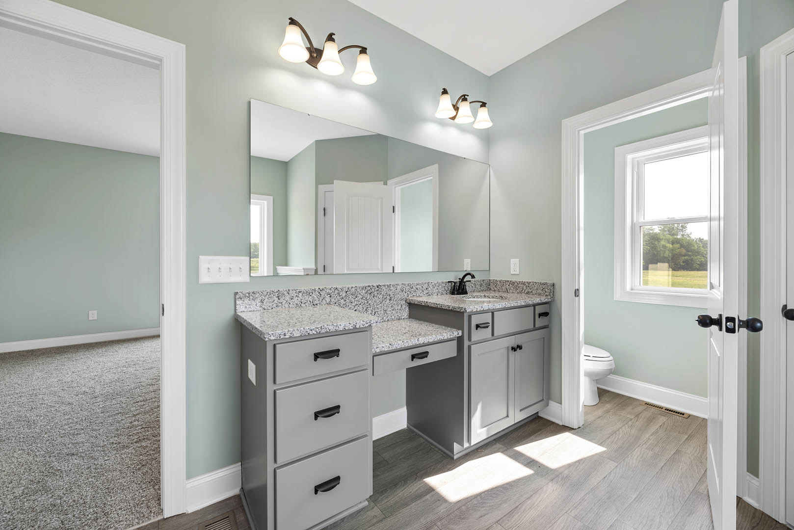 Bathroom featuring marble countertop, large mirror above vanity, close-up of drawer with sleek hardware, three-light fixture, white rectangular control panel with black buttons