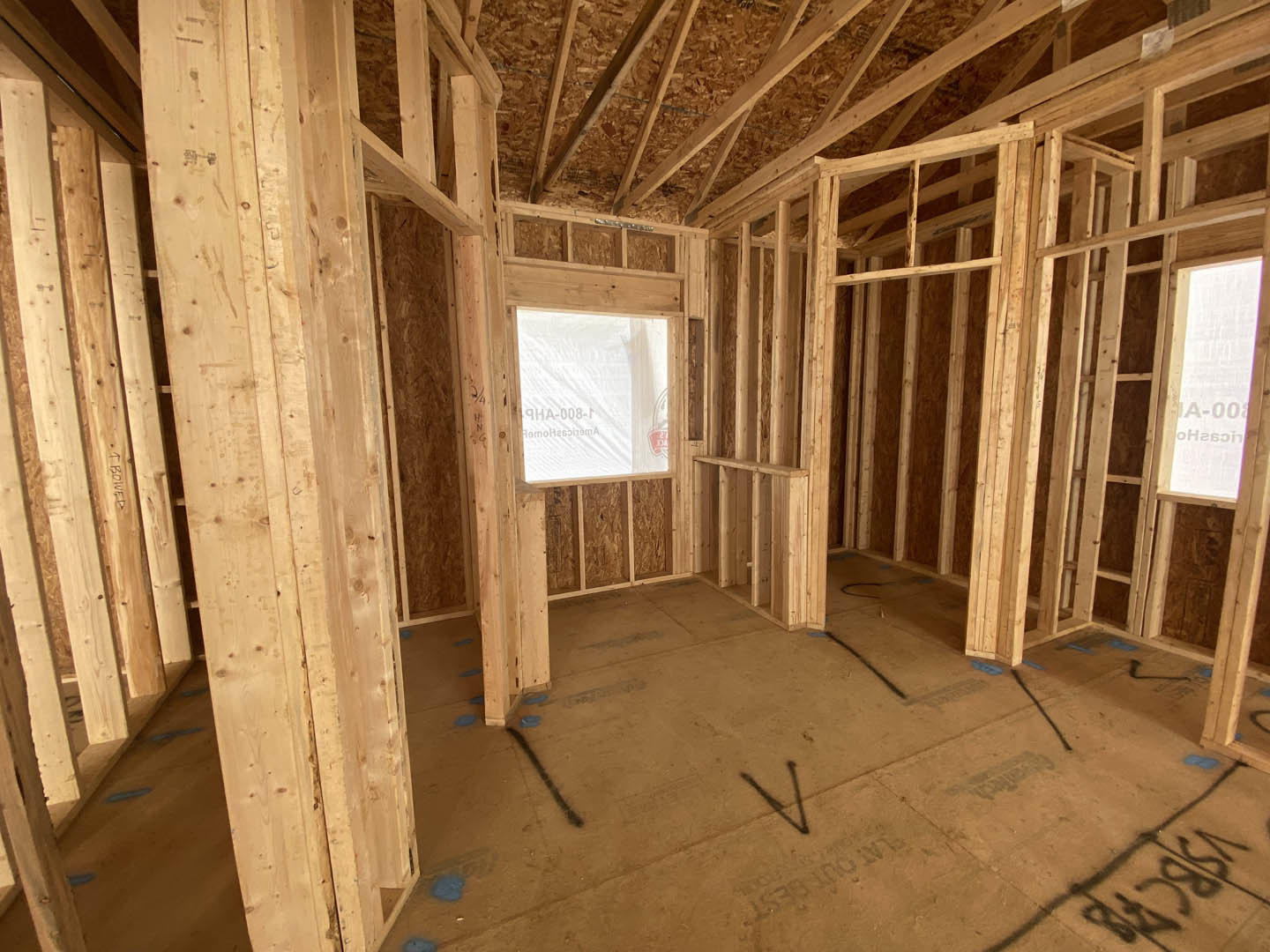 Living room with exposed wood ceiling beams, large window, light-colored walls, and hardwood flooring