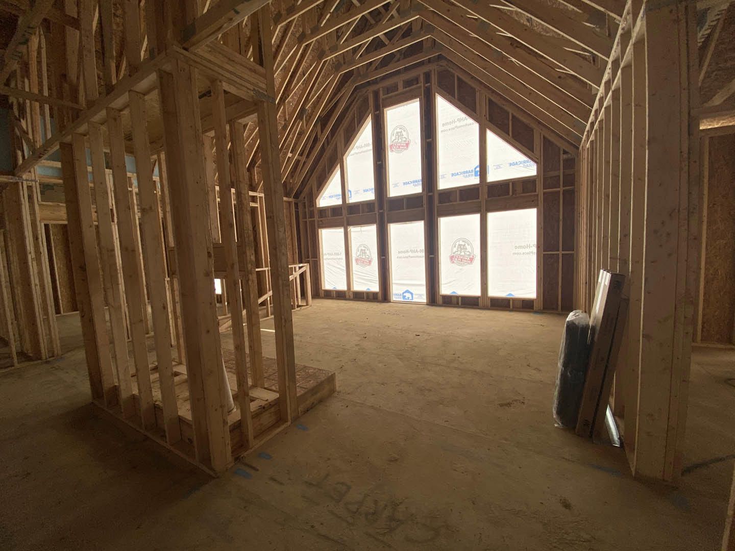 Open room with exposed wood ceiling beams, large window, and light-colored walls.