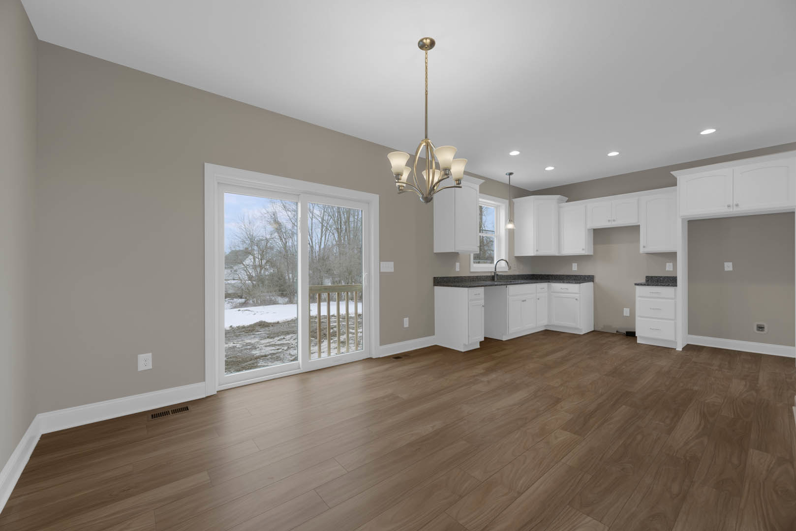 White cabinetry with silver handles, hardwood flooring, ceiling chandelier, sliding glass door revealing snowy landscape, window providing natural light