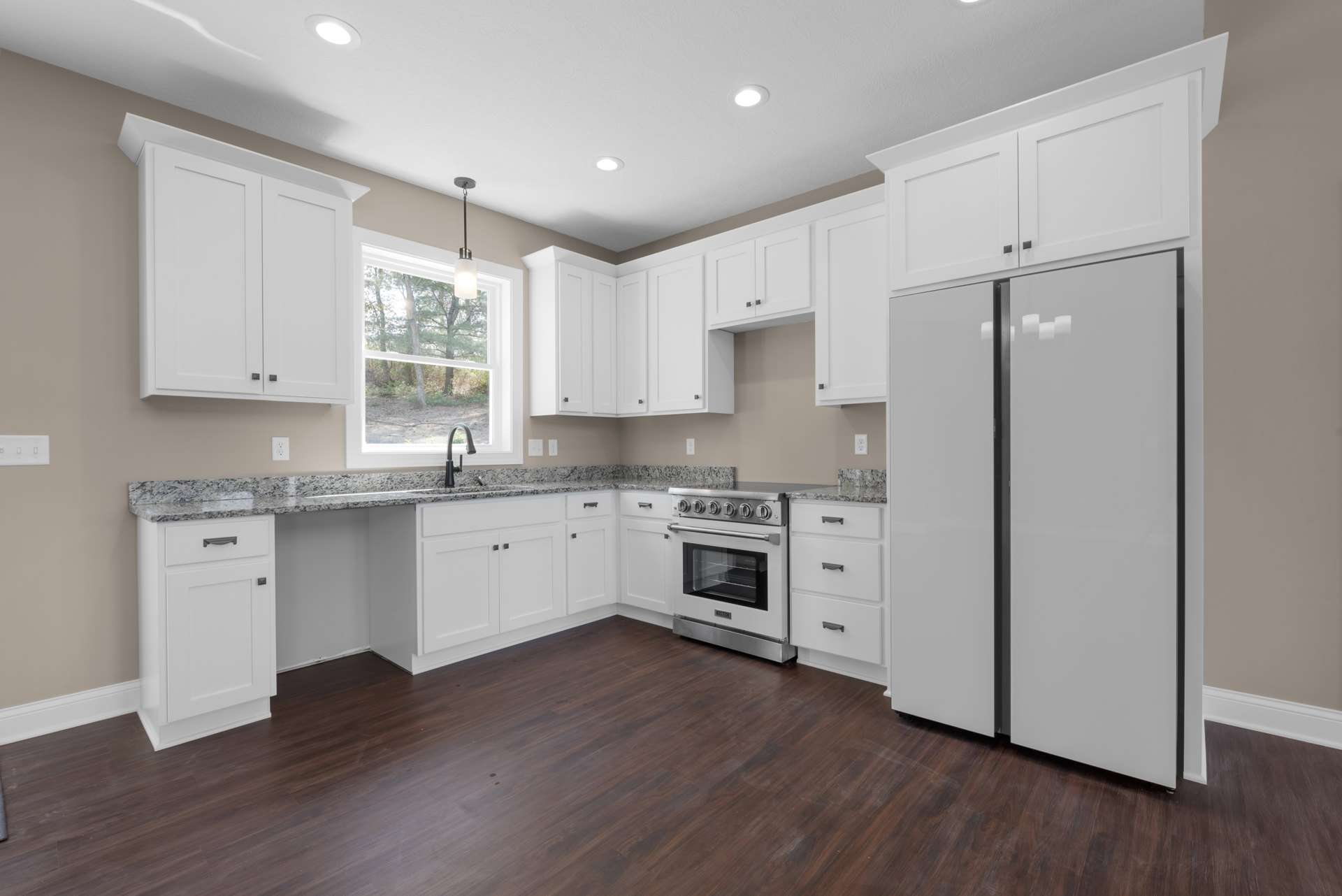 White kitchen with black-handled cabinets, granite countertops, wood flooring, white stove with glass door, and white refrigerator with black trim.