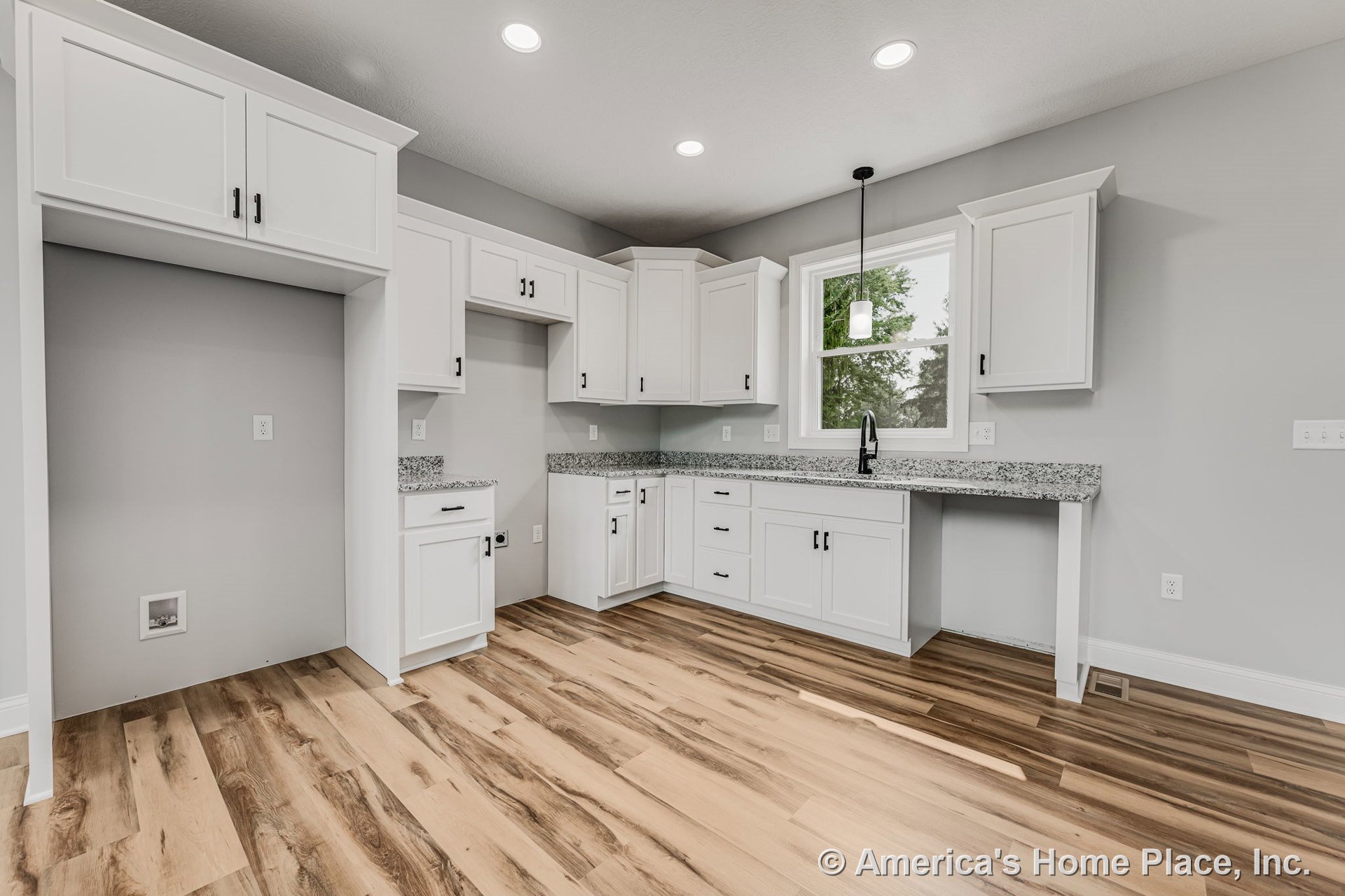 White shaker-style upper and lower cabinets with granite countertops, wood-look vinyl plank flooring, recessed ceiling lights, single pendant light above the sink, and a large