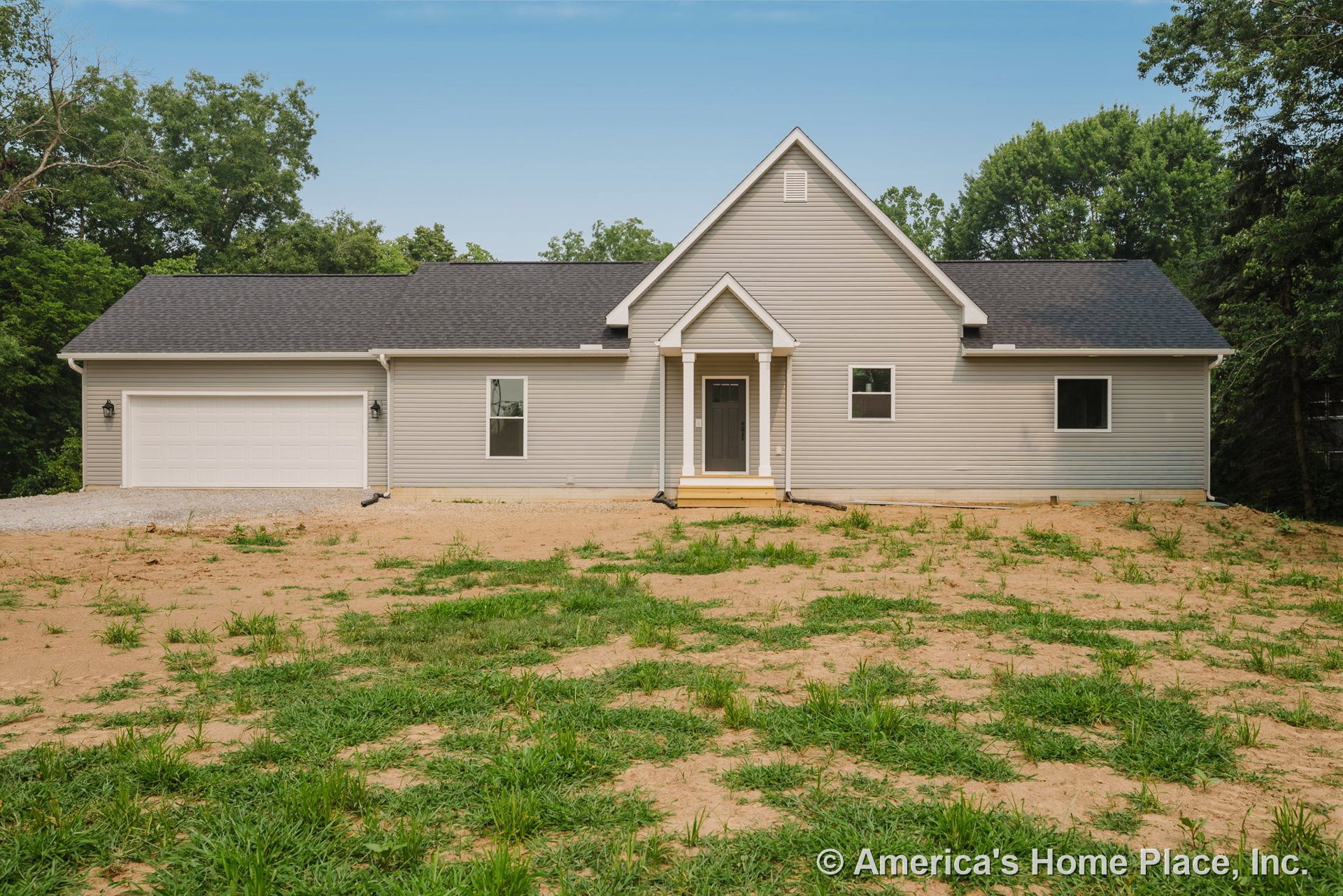 Light gray vinyl siding exterior with white trim and gutters, covered front porch supported by columns, attached two-car garage, black shingle roof, rectangular windows, and a