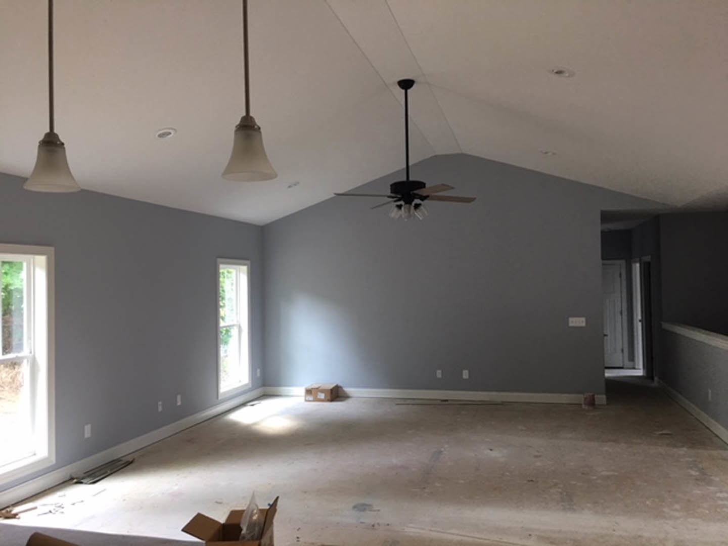 Neutral-toned room with plaster walls, ceiling fan with light fixture, large window, and hardwood flooring