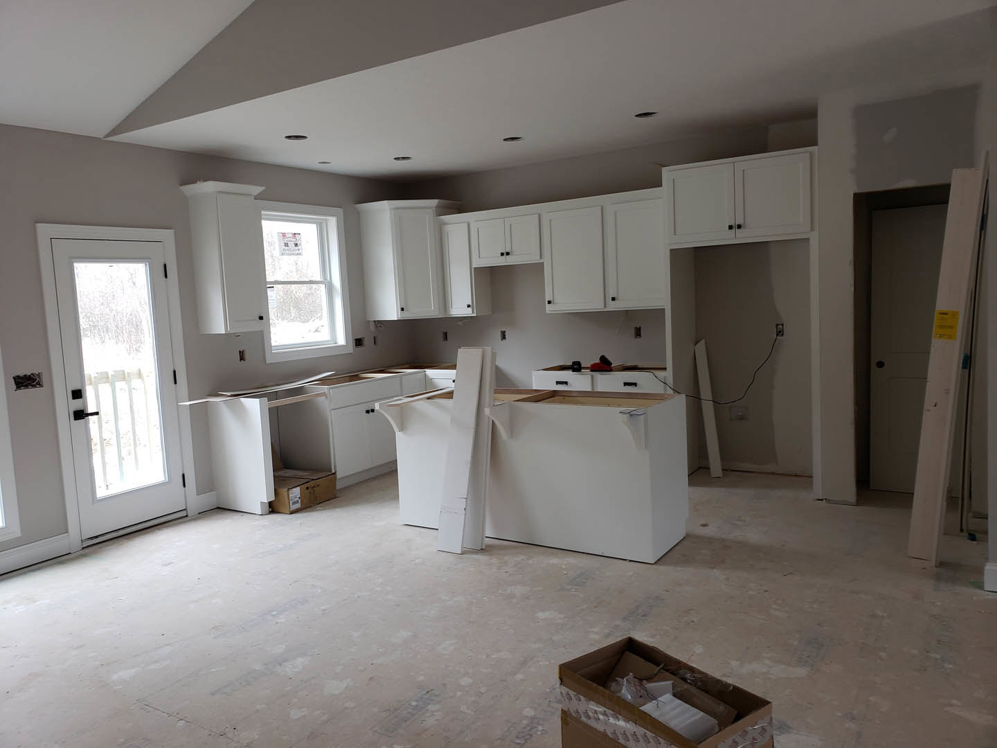 Kitchen with white shaker cabinets, white tile flooring, black cabinet handles, stainless steel sink, and a window above the counter.