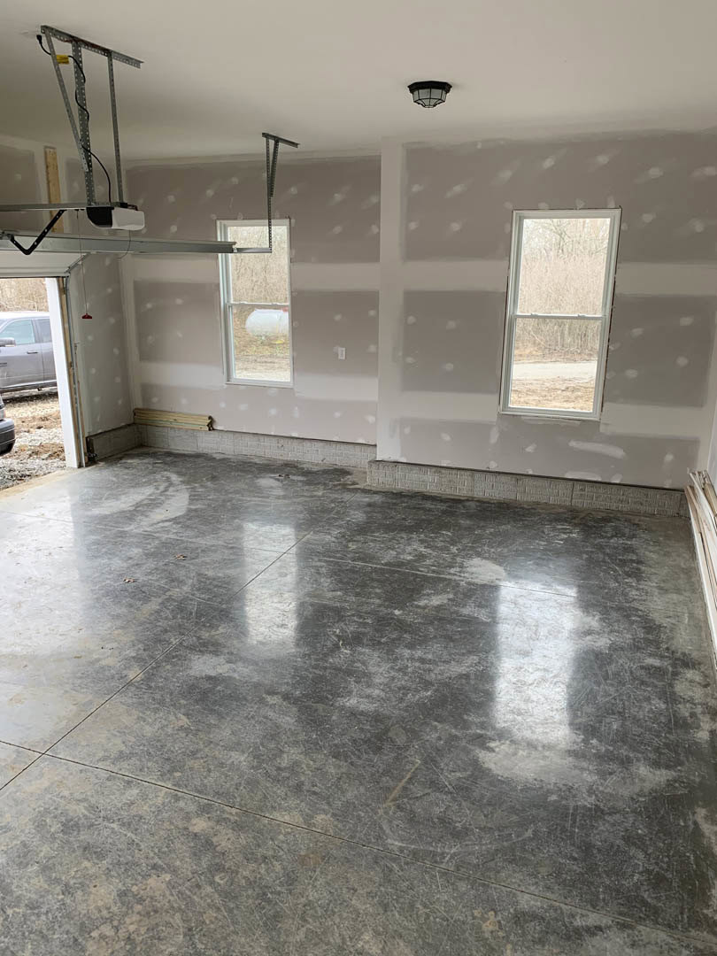 Concrete floor with white baseboard trim, large window featuring frosted glass and white frame, smooth plaster walls in a modern interior room