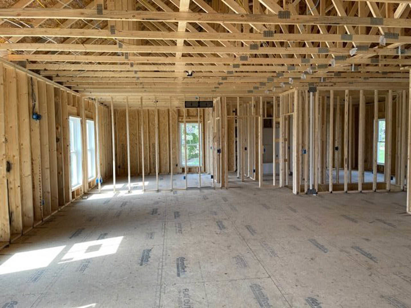 Living room with exposed wood ceiling beams, large windows, and hardwood flooring